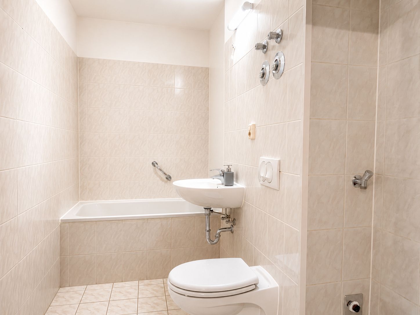 Helles Badezimmer mit Badewanne, Waschbecken und Toilette, alles aus weißer Keramik.