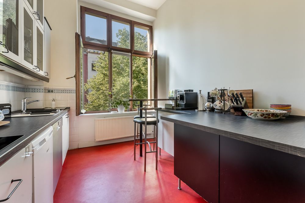 Moderne Küche mit roten Boden, großem Fenster, Theke und verschiedenen Küchengeräten.
