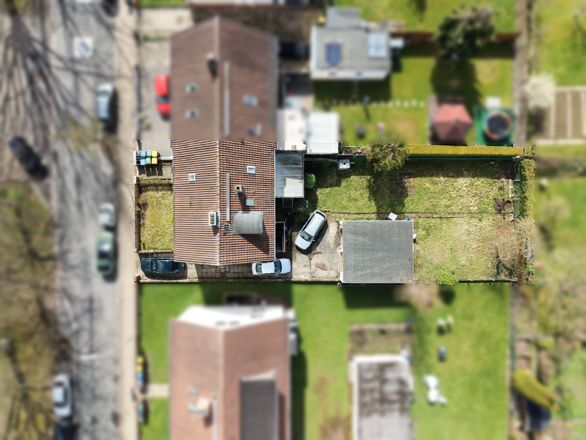Luftaufnahme eines Wohnhauses mit Garten, Einfahrt und geparktem Auto.