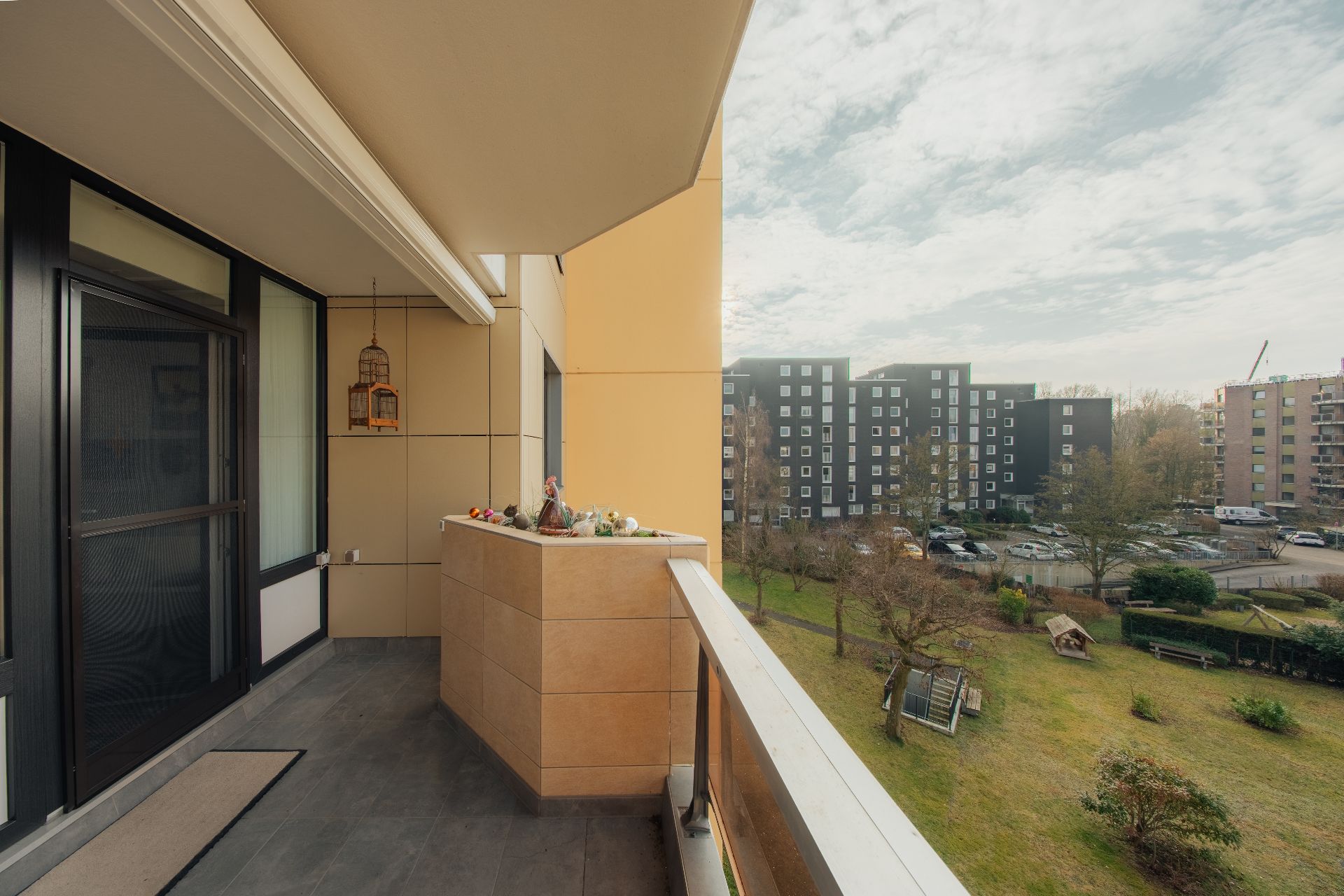 Balkon mit Geländer und Blick auf Grünfläche und Wohngebäude im Hintergrund.