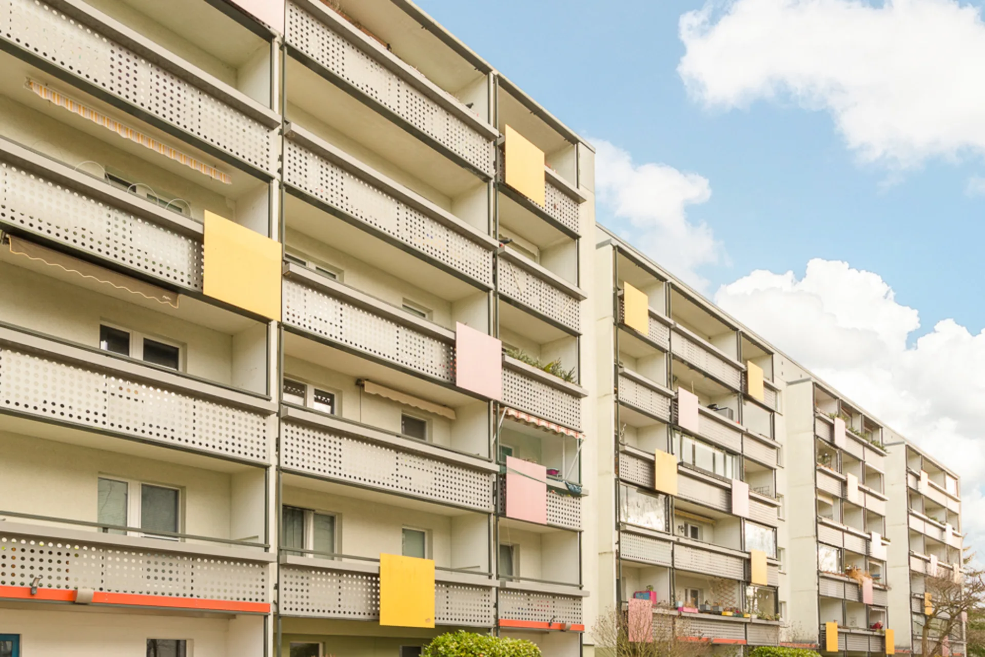 Mehrstöckiges Wohngebäude mit Balkonen und bunten Paneelen an den Geländern.