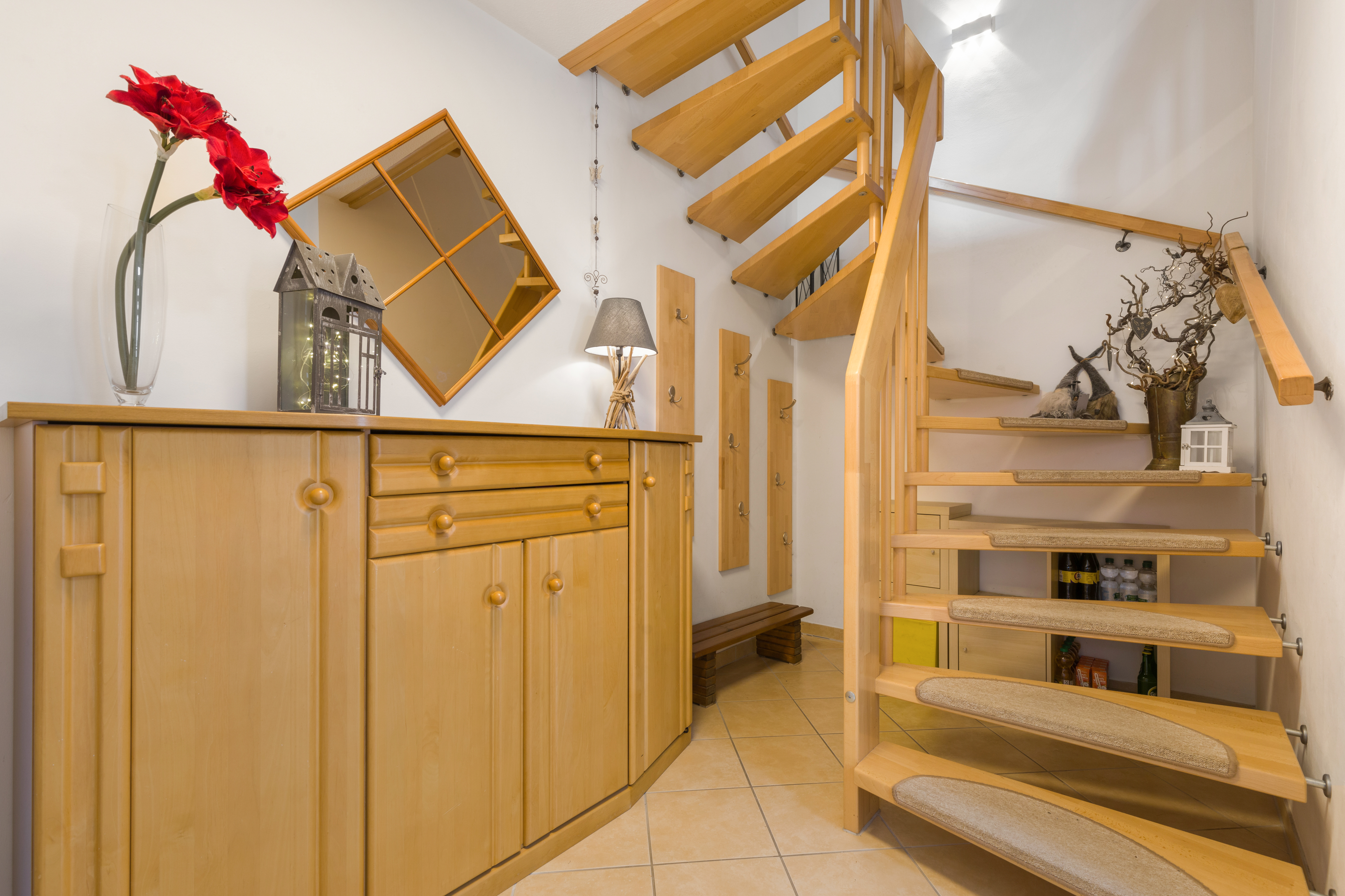 Holztreppe und Flur mit Sideboard, Spiegel, Garderobe und Dekorationen.