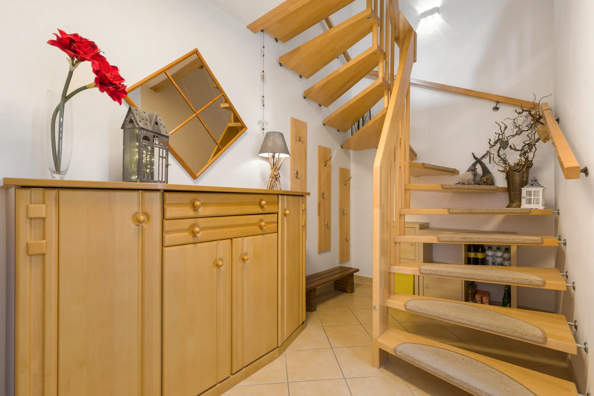 Holztreppe und Flur mit Sideboard, Spiegel, Garderobe und Dekorationen.