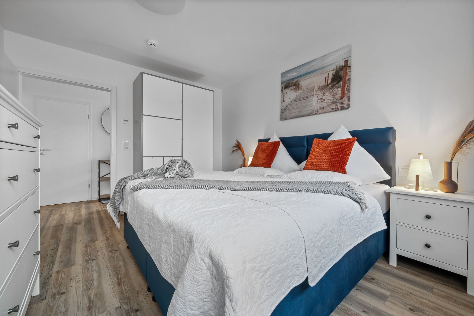 Modernes Schlafzimmer mit Doppelbett, weißem Schrank, Nachttisch und Dekoration.