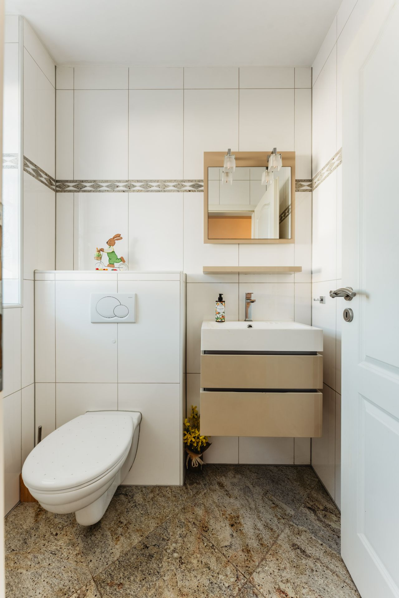 Modernes, kleines Badezimmer mit Wandtoilette, Waschbecken und Spiegel.