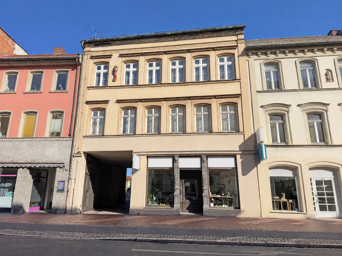 Dreistöckiges Wohnhaus mit großen Fenstern und Ladengeschäften im Erdgeschoss.