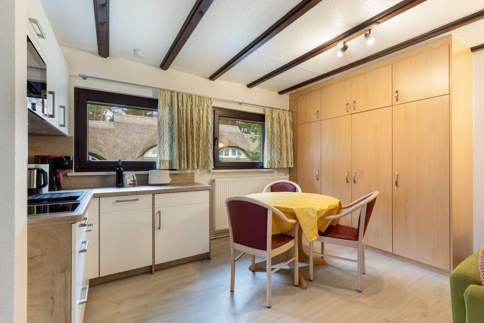 Kleine Küche mit Esstisch, vier Stühlen und einem großen Holzschrank an der Wand.