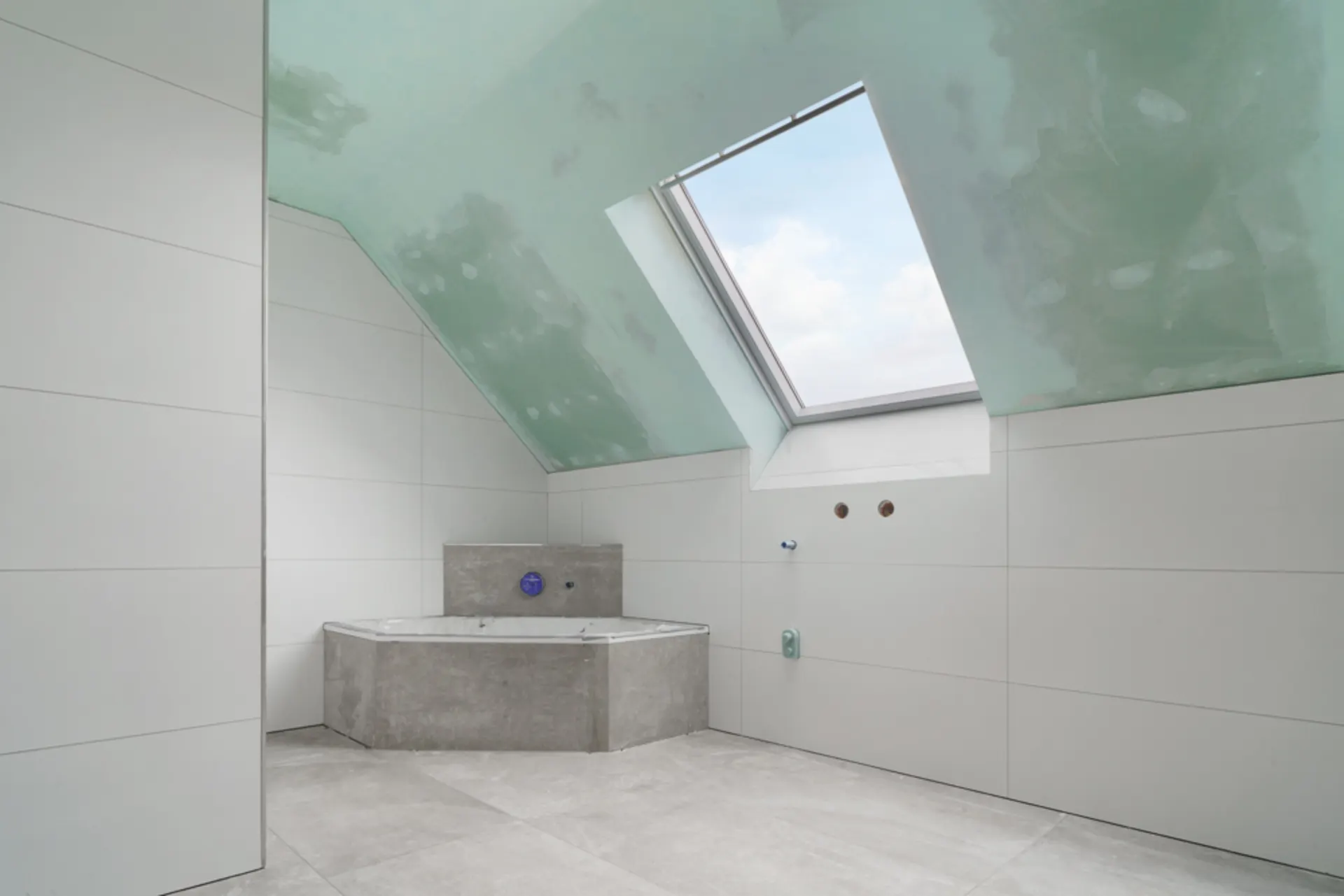 Modernes Badezimmer mit Eckbadewanne und großem Dachfenster unter einer schrägen Decke.