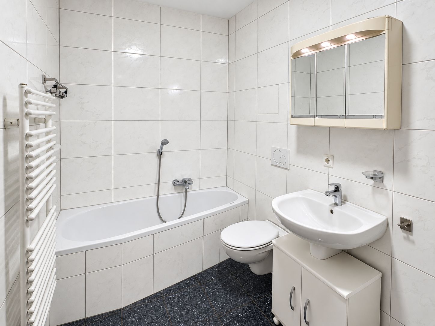 Helles Badezimmer mit Badewanne, Waschbecken, Spiegel und Toilette.