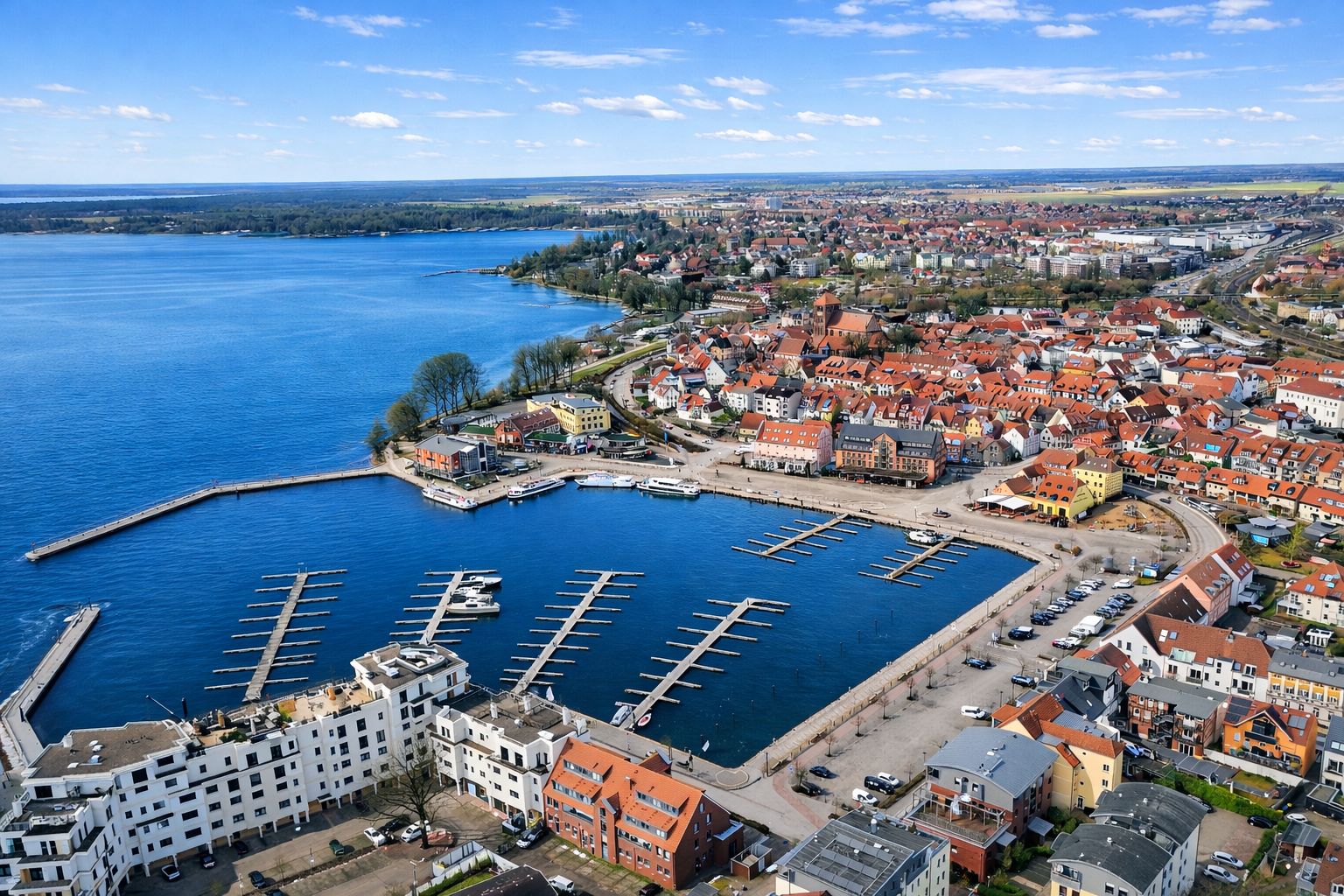 Luftaufnahme eines Yachthafens mit Bootsstegen und angrenzender Wohnsiedlung am Wasser.