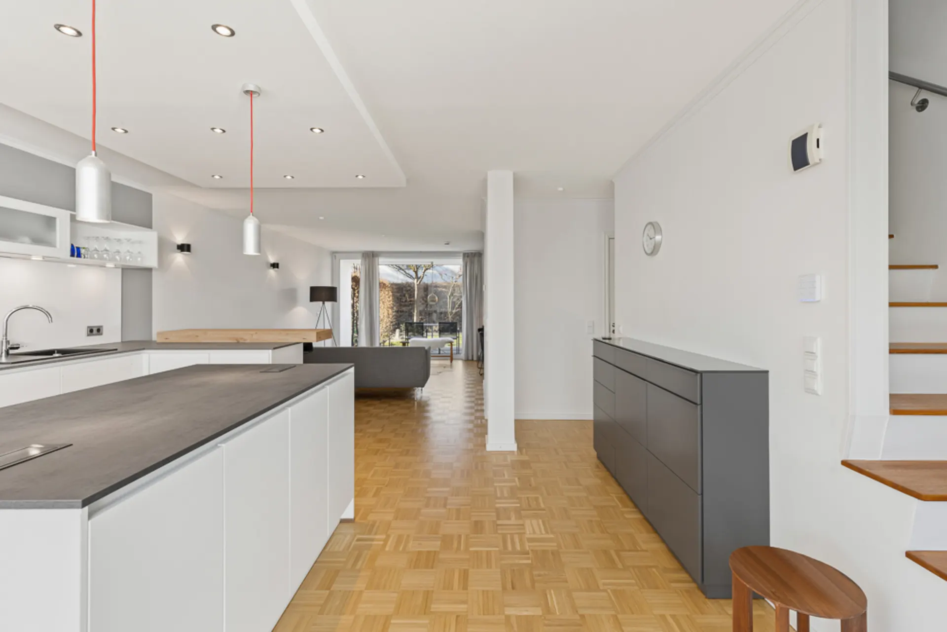 Moderne offene Küche und Wohnbereich mit großem Fenster und Parkettboden.