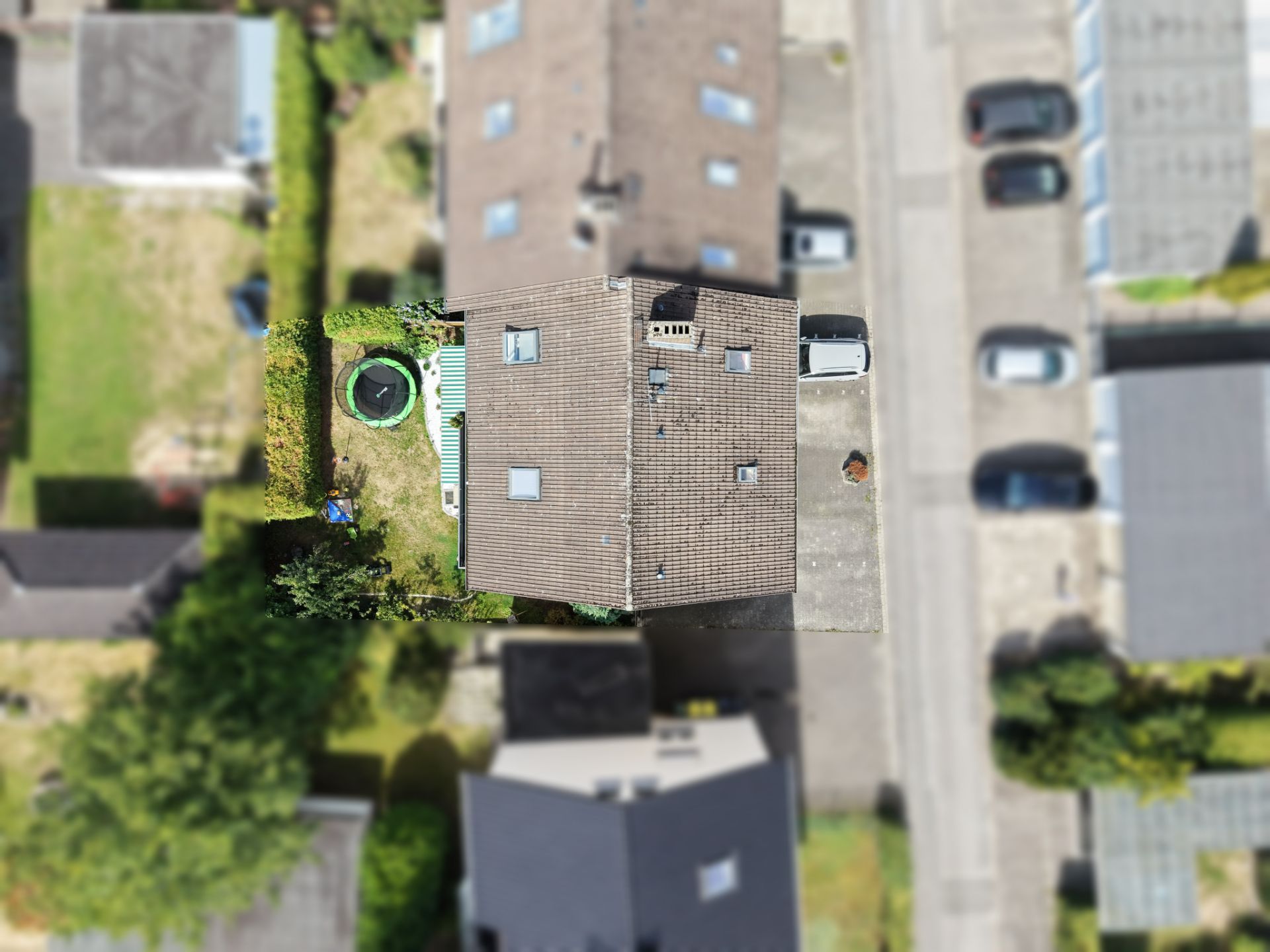 Luftaufnahme eines Wohnhauses mit Garten, Trampolin und angrenzender Einfahrt.