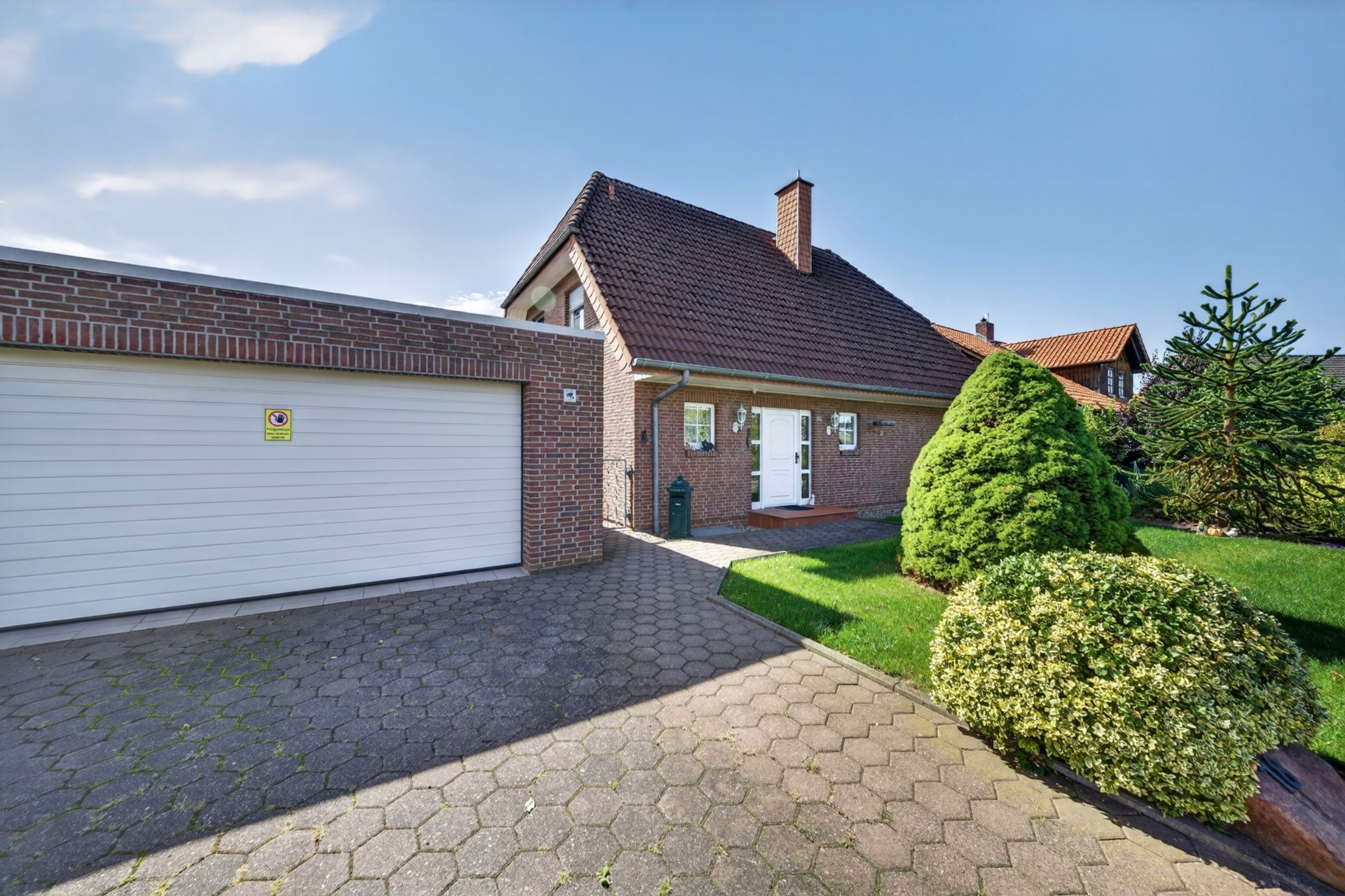 Einfamilienhaus mit rotem Dach, großer Garage und gepflegtem Vorgarten.