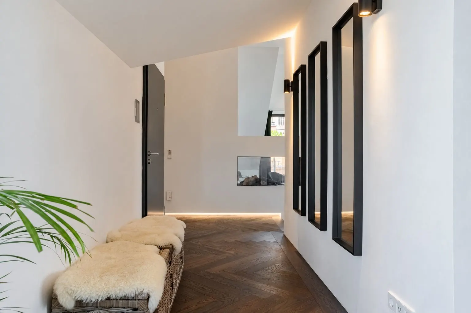 Moderner Flur mit Holzboden, Spiegeln an der Wand und Bank mit Kissen.