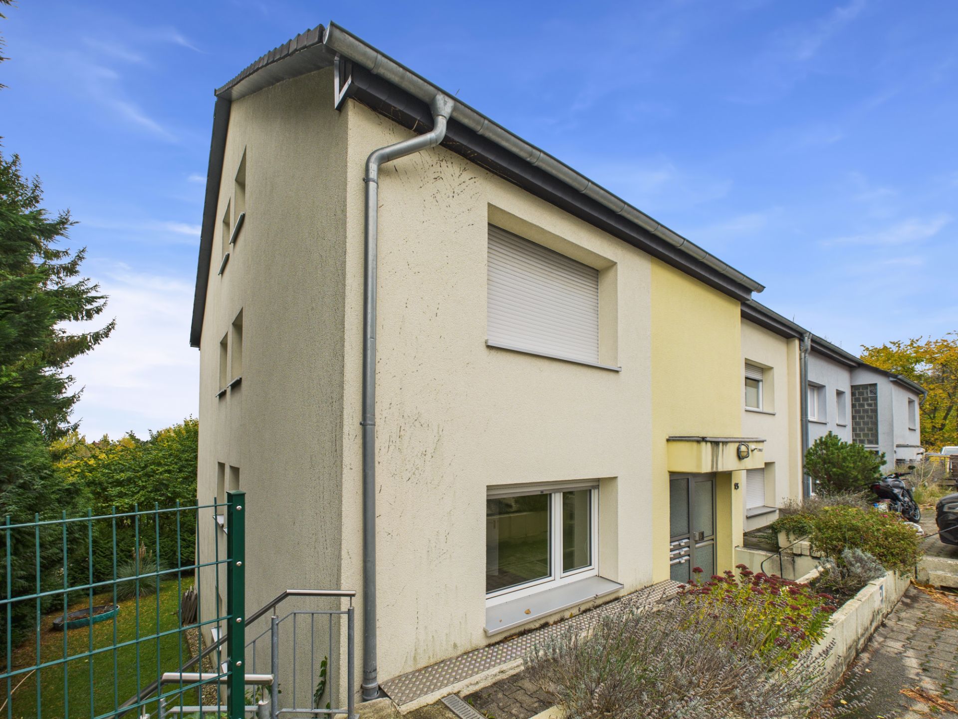 Außenansicht eines Reihenhauses mit Vorgarten und Rollläden an den Fenstern.