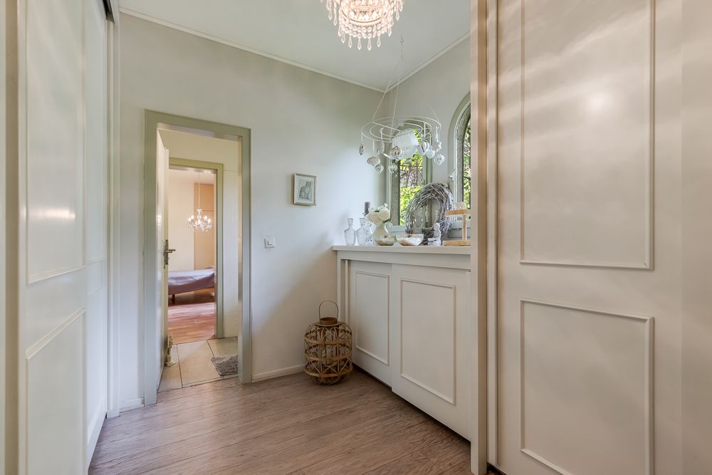 Heller Flur mit Holzfußboden, weißen Schränken und Blick in ein Schlafzimmer.