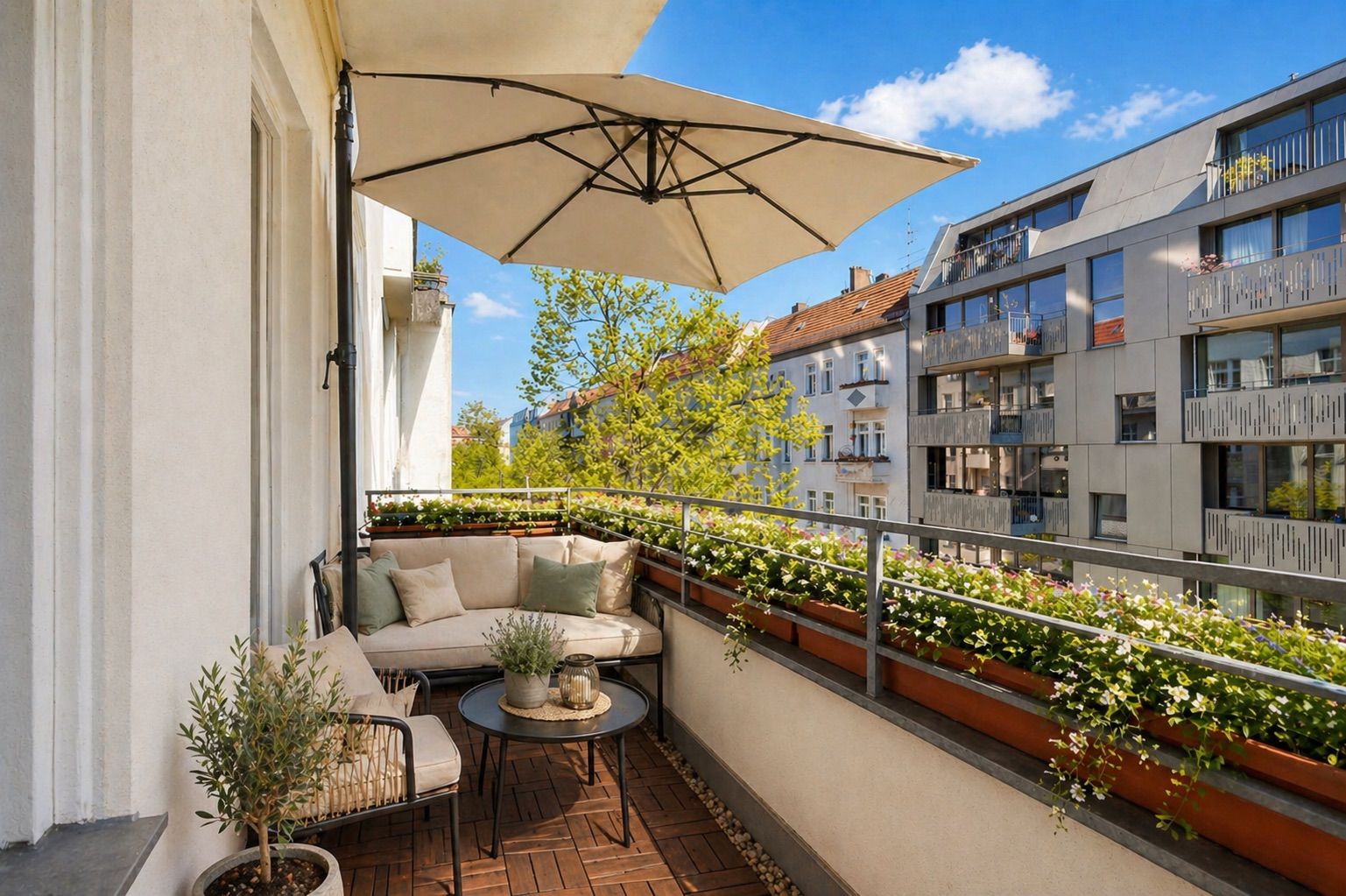 Balkon mit Sofa, Tisch, Pflanzen und großem Sonnenschirm, Blick auf andere Wohnhäuser.