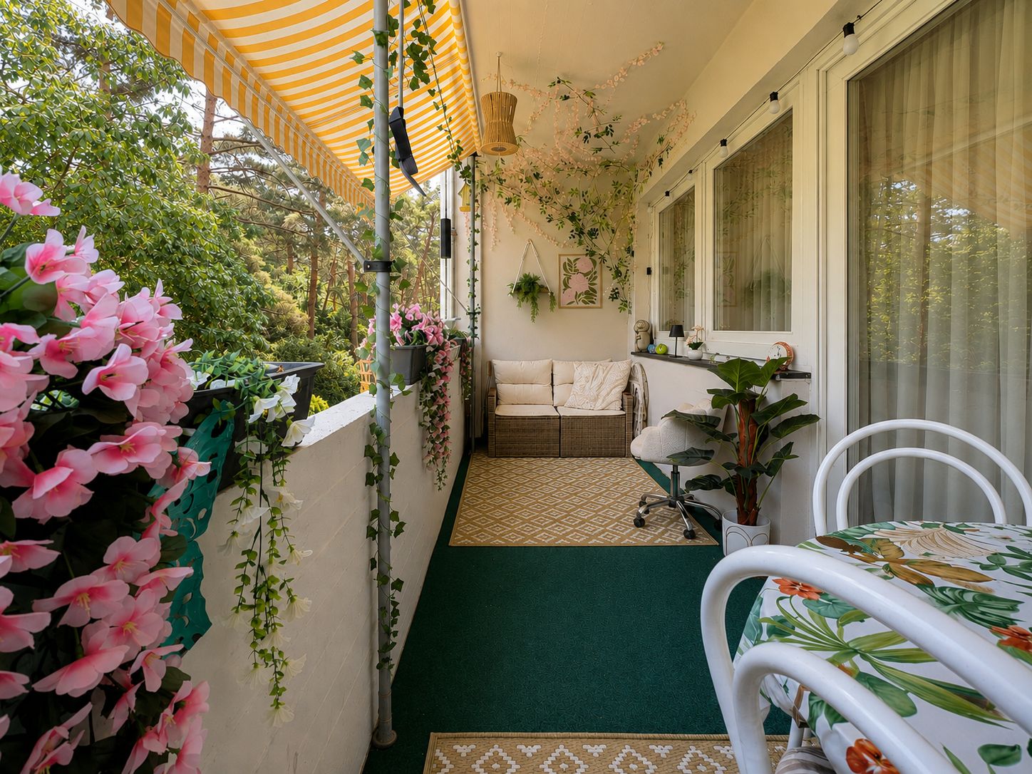 Balkon mit Sitzbank, Tisch, Blumen und Markise, Blick ins Grüne.