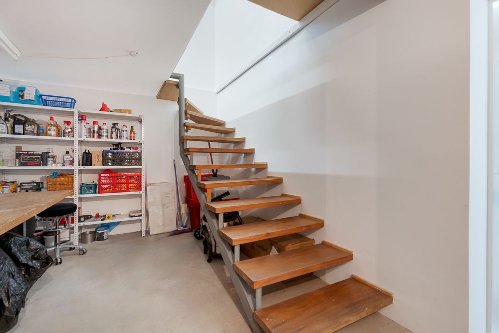 Holztreppe neben Regal mit Haushaltsartikeln in einem Kellerraum.