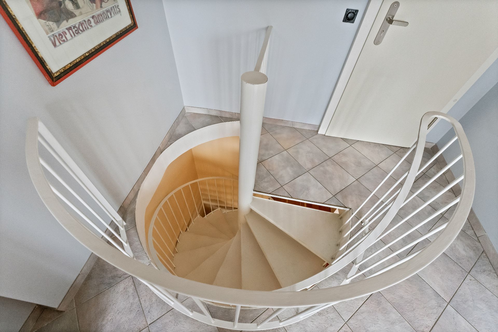 Weiße Wendeltreppe in einem Flur mit Fliesenboden und weißen Wänden.
