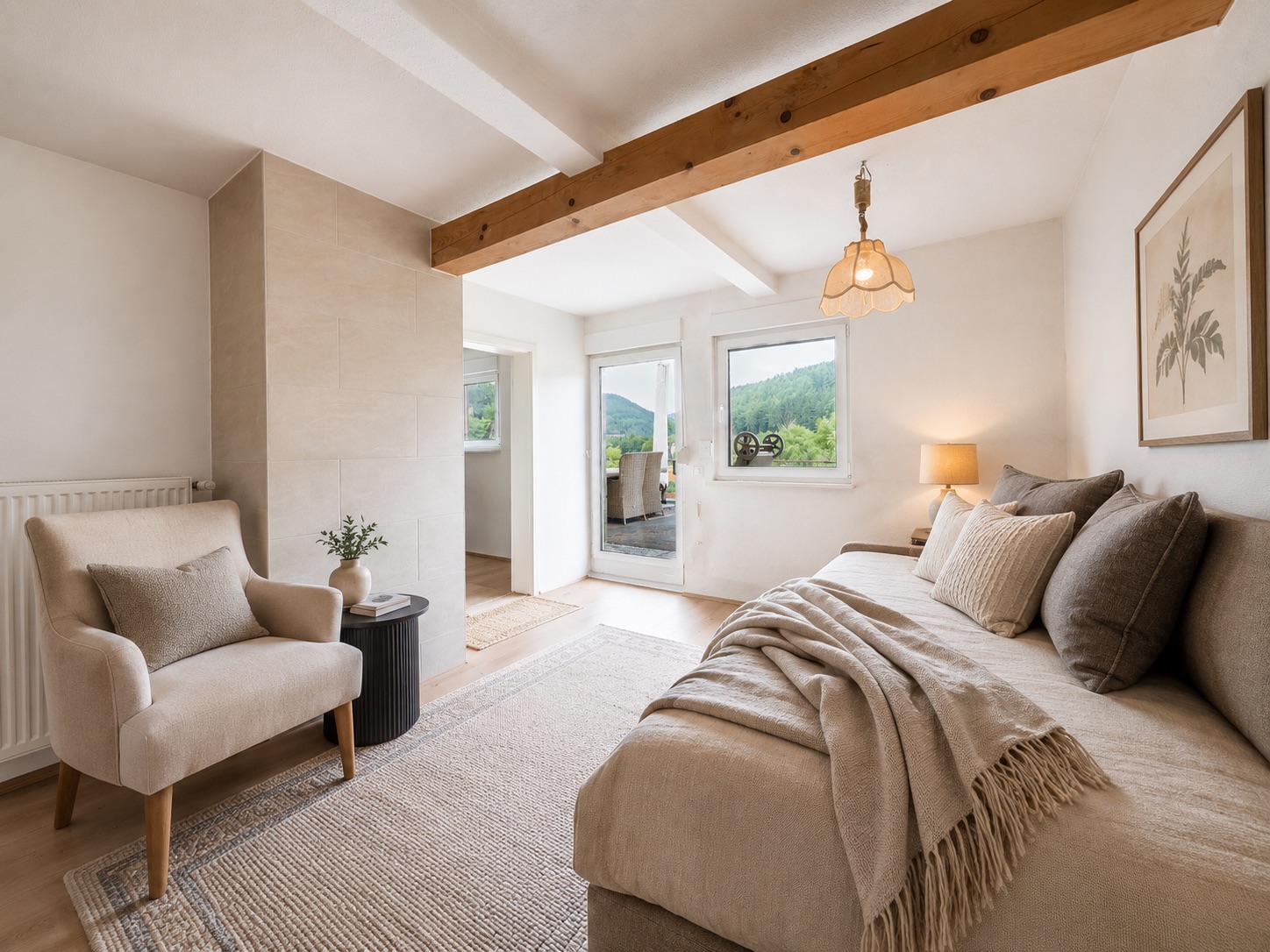 Helles Wohnzimmer mit Sofa, Sessel, Teppich und Fenster mit Blick ins Grüne.