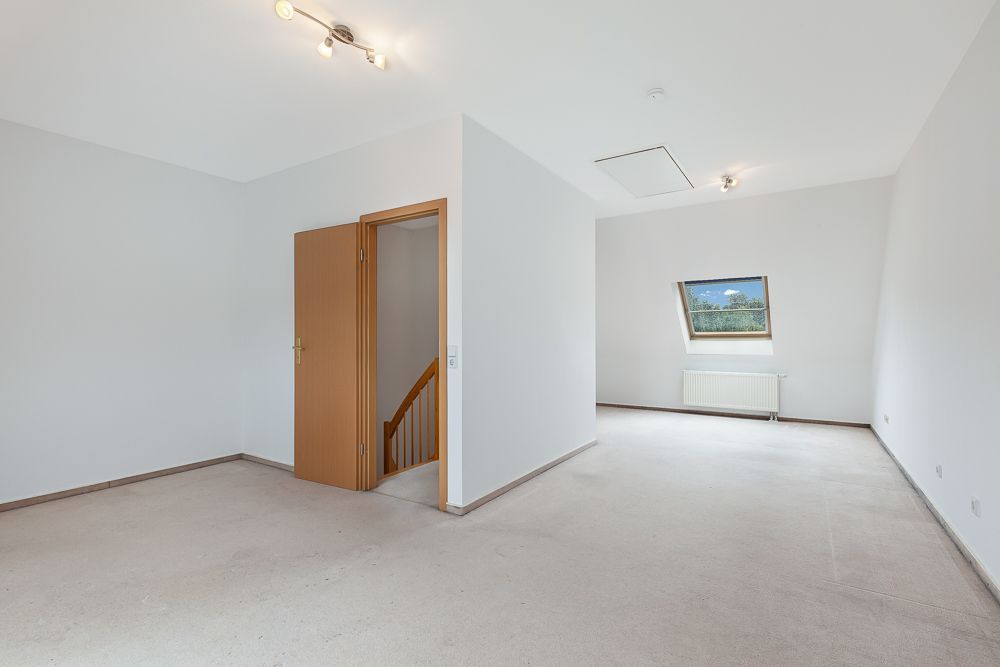 Leerer, heller Raum mit weißem Wänden, offenem Fenster, Treppe und Heizung.
