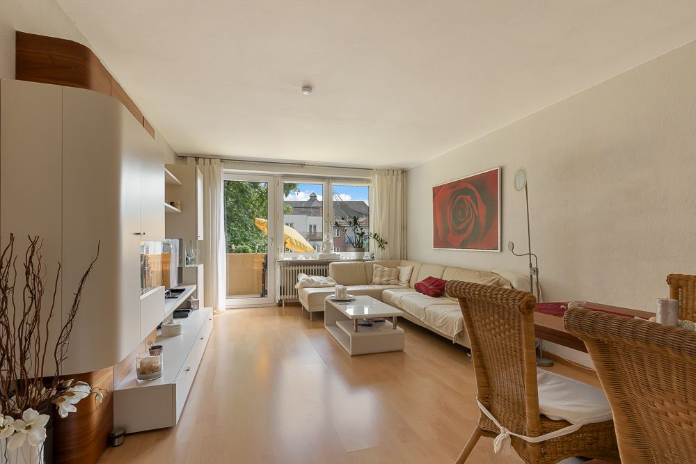 Helles Wohnzimmer mit Sofa, Couchtisch, TV-Möbel und großem Fenster zum Balkon.
