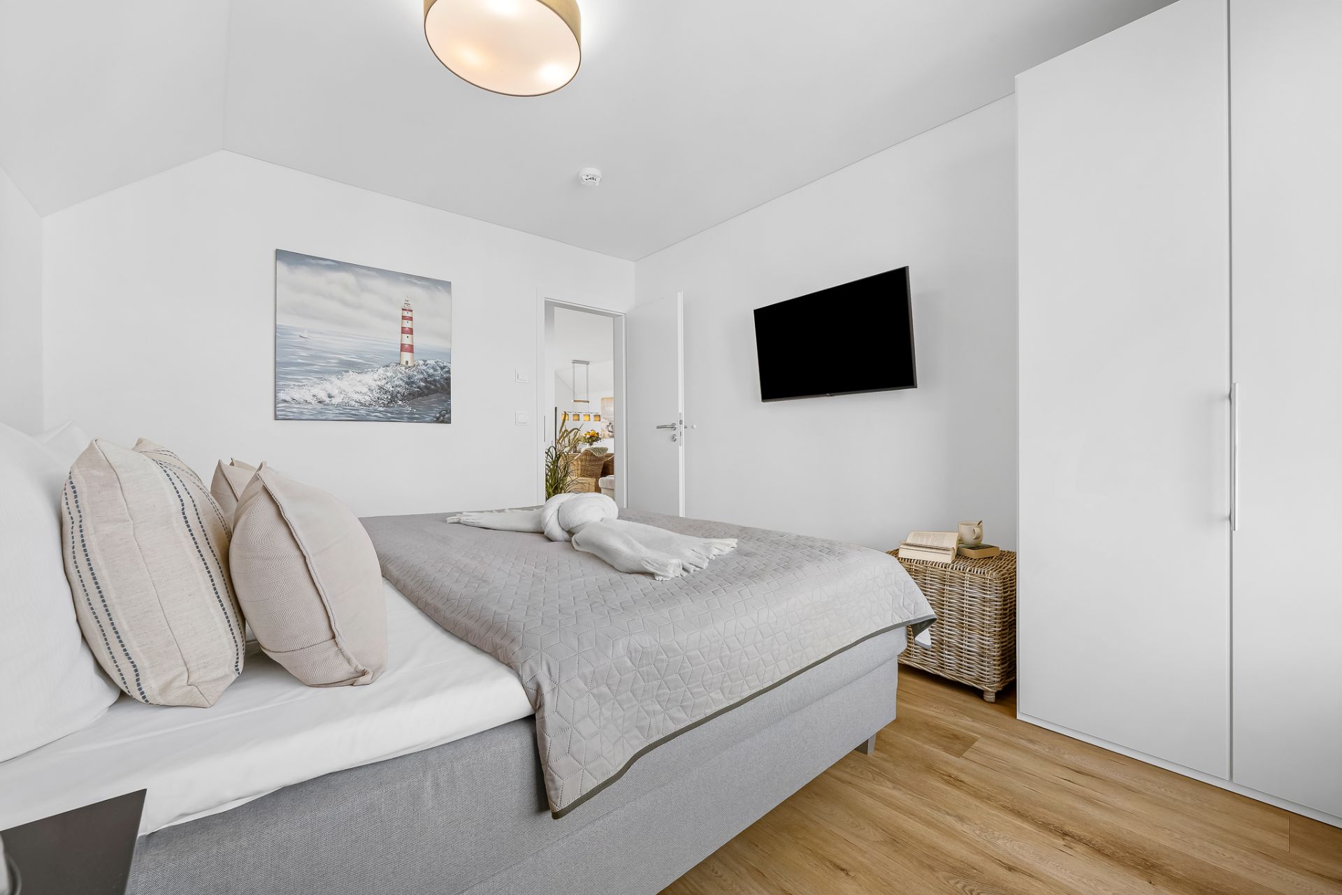 Modernes Schlafzimmer mit Doppelbett, TV, Kleiderschrank und dekoriertem Bild an der Wand.
