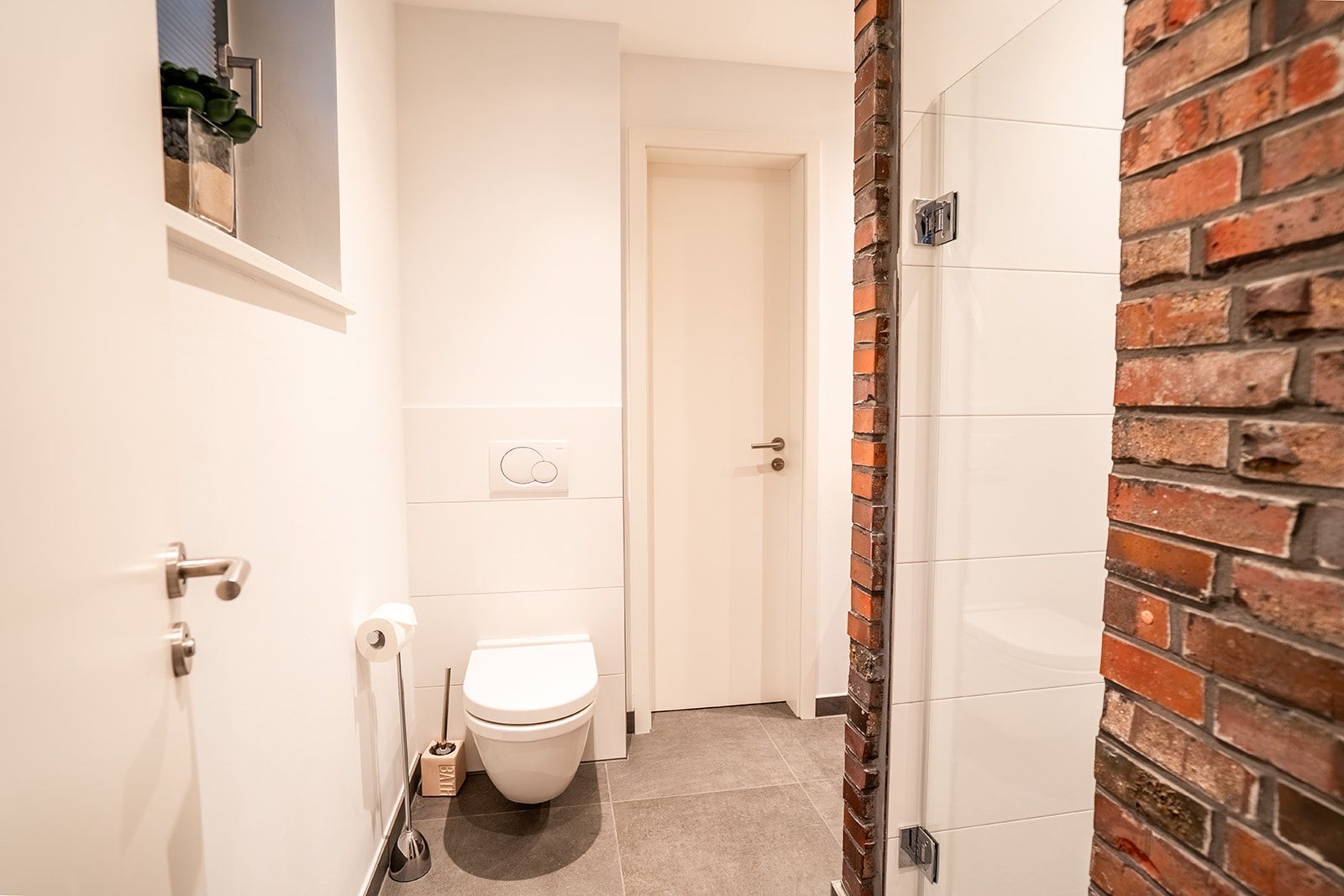 Modernes Badezimmer mit WC, Toilettenpapierhalter und Dusche mit Glastür.