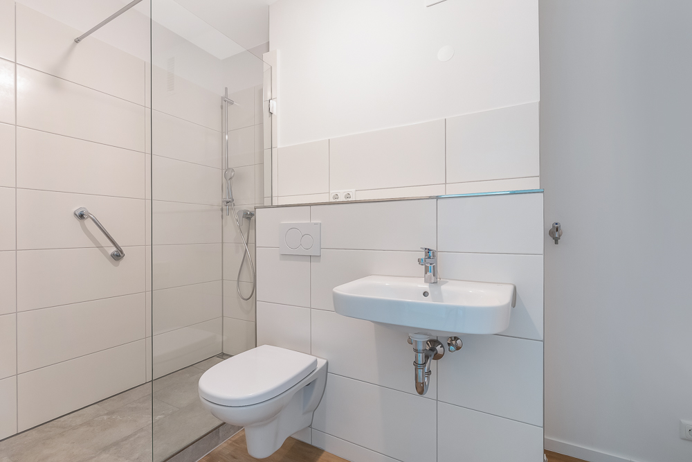 Modernes, barrierefreies Badezimmer mit Dusche, WC und Waschbecken.