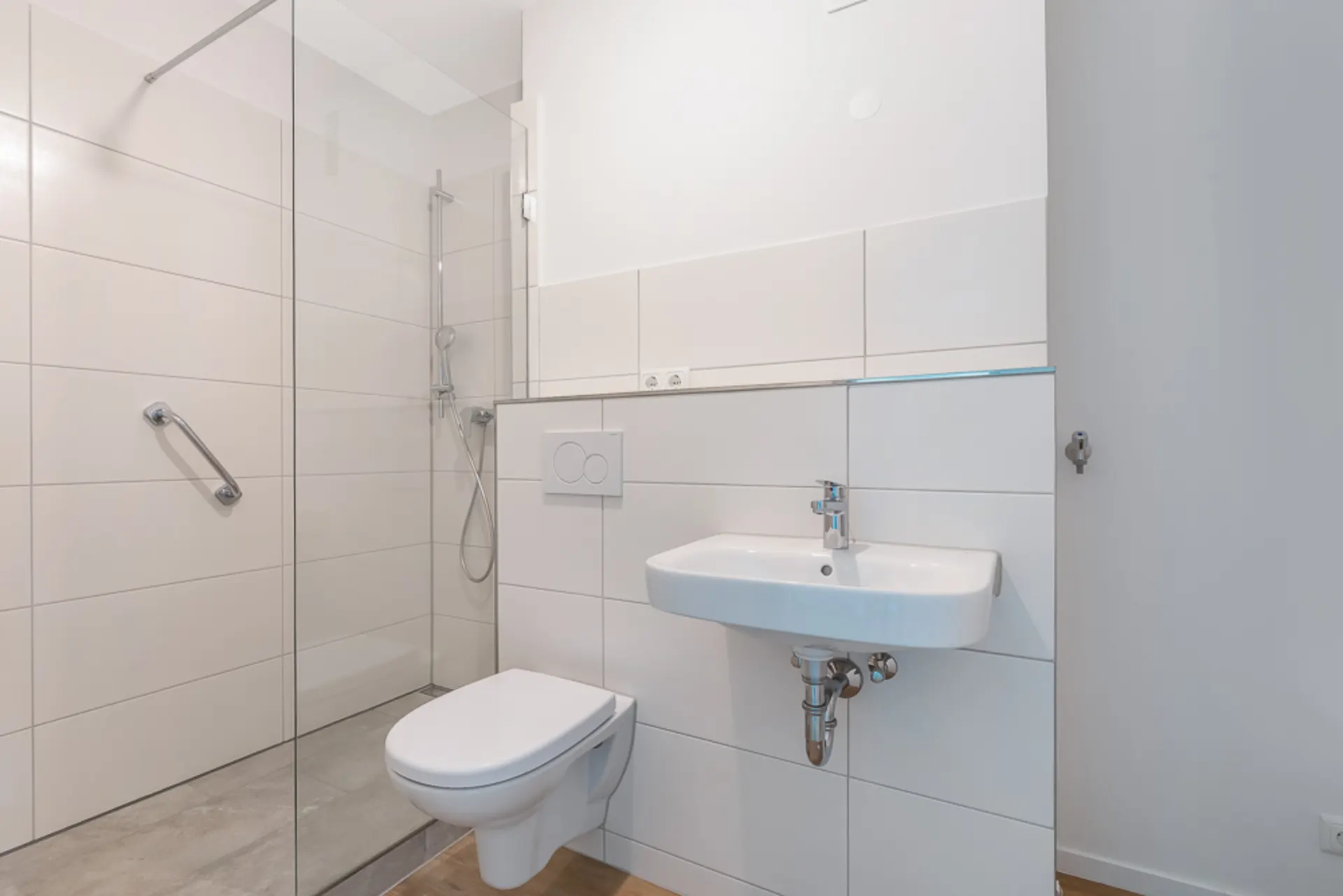 Modernes, barrierefreies Badezimmer mit Dusche, WC und Waschbecken.