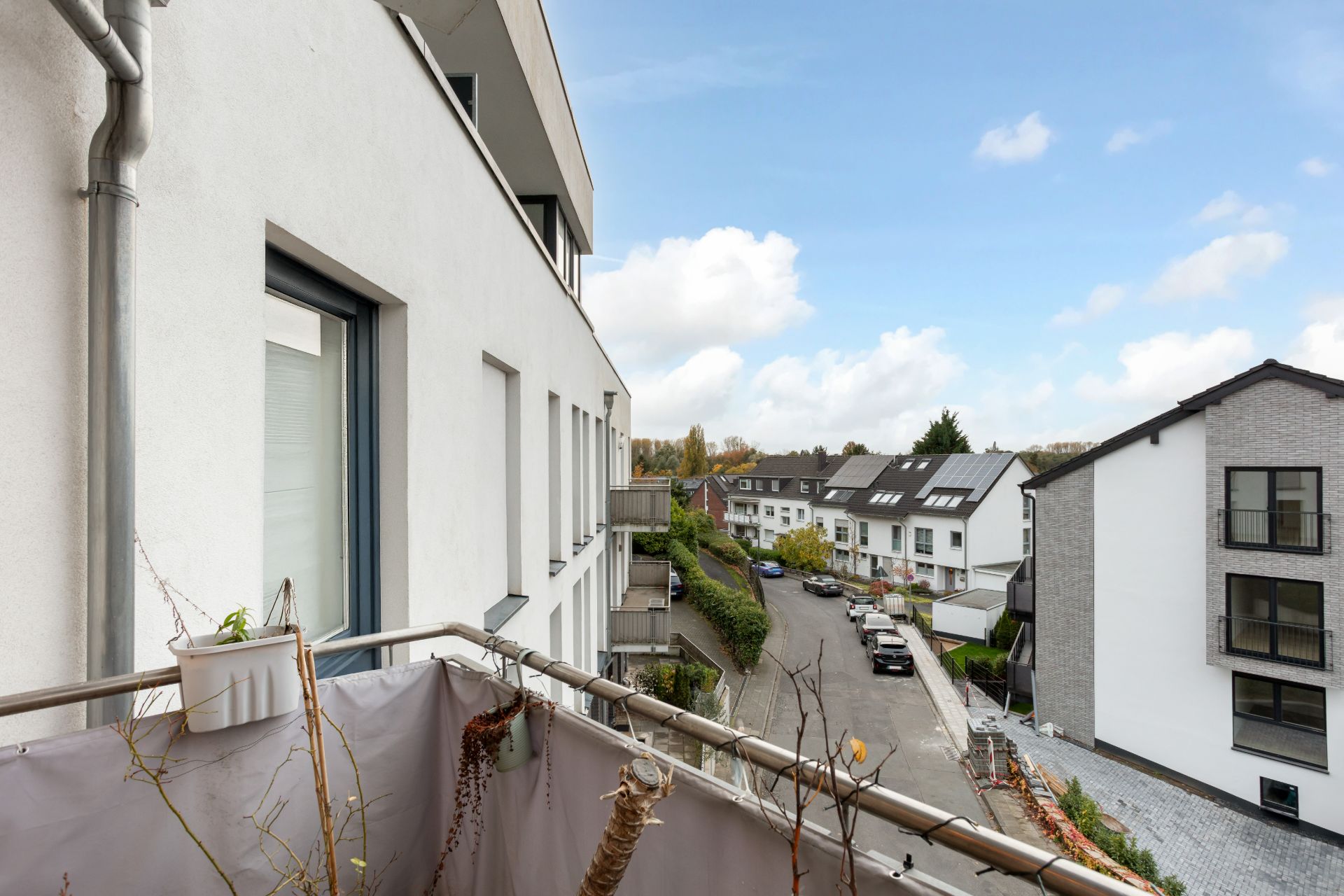 Blick von einem Balkon auf eine ruhige Wohnstraße mit modernen Häusern.