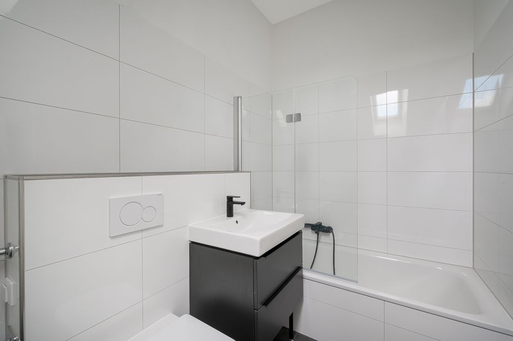 Modernes Bad mit Waschbecken, Badewanne und weißen Wandfliesen.