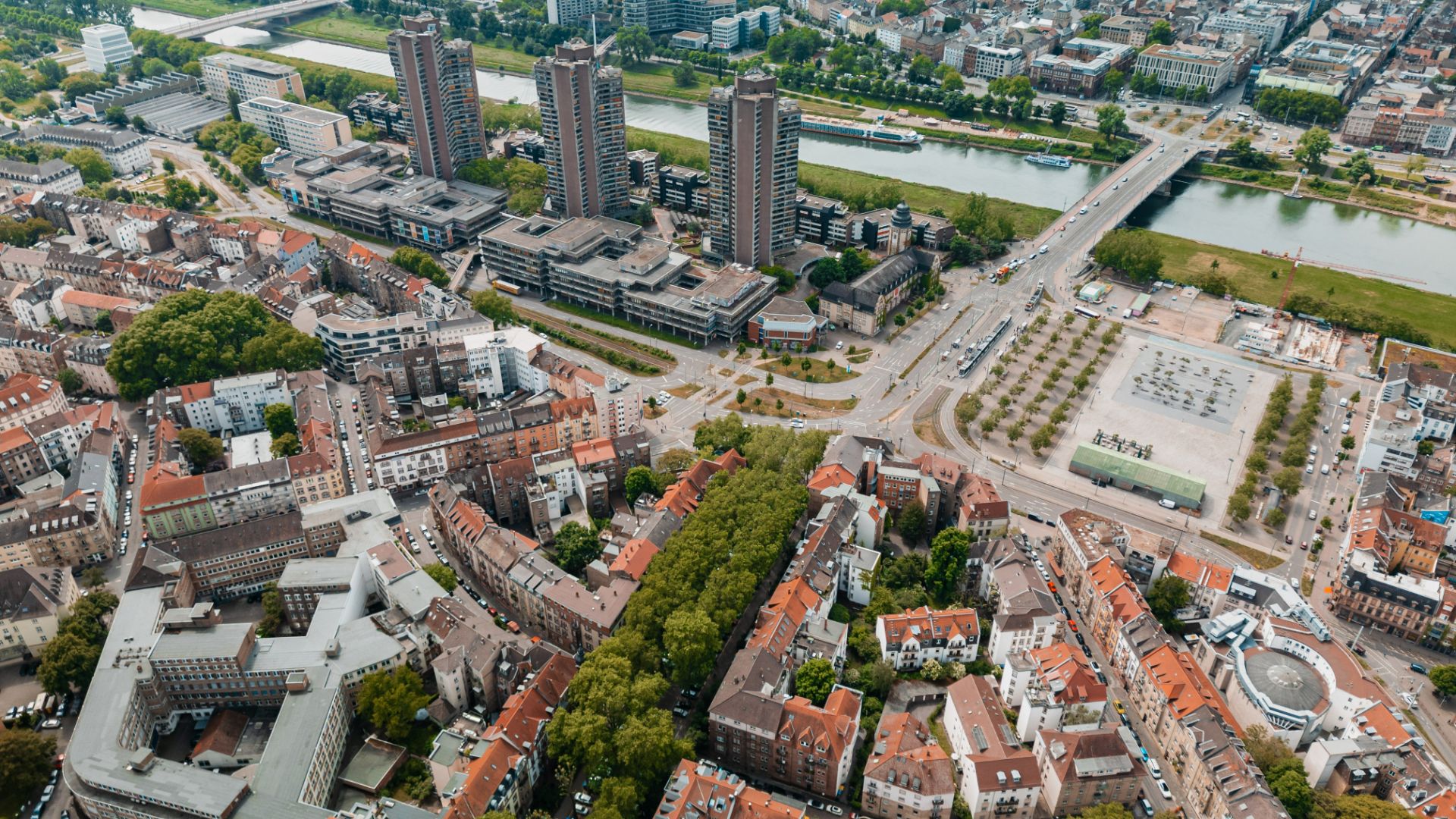 Luftaufnahme einer Stadt mit Fluss, Wohnhäusern und Hochhäusern.