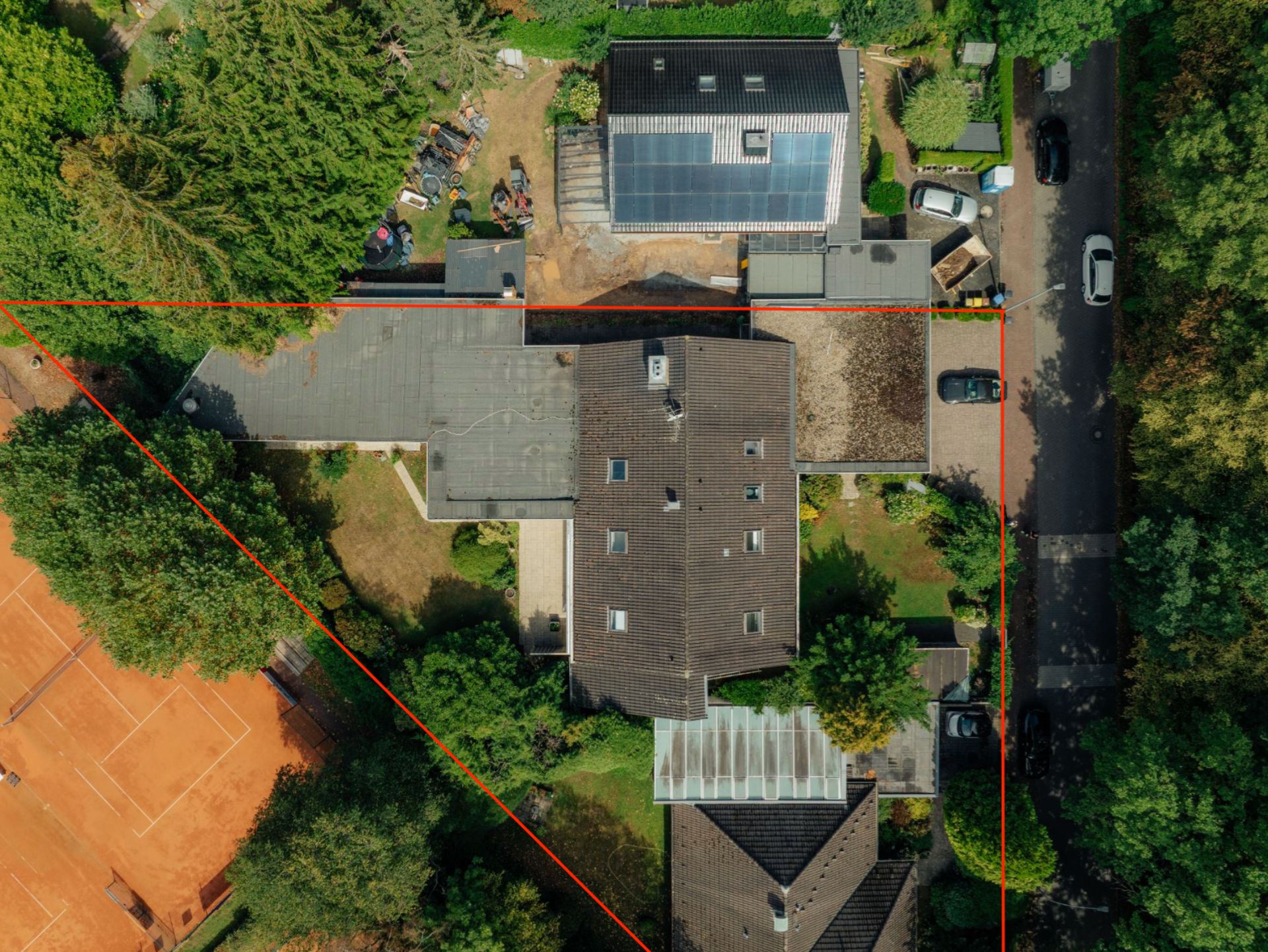 Luftbild eines Wohnhauses mit Garten, Nebengebäuden und markiertem Grundstücksrand.