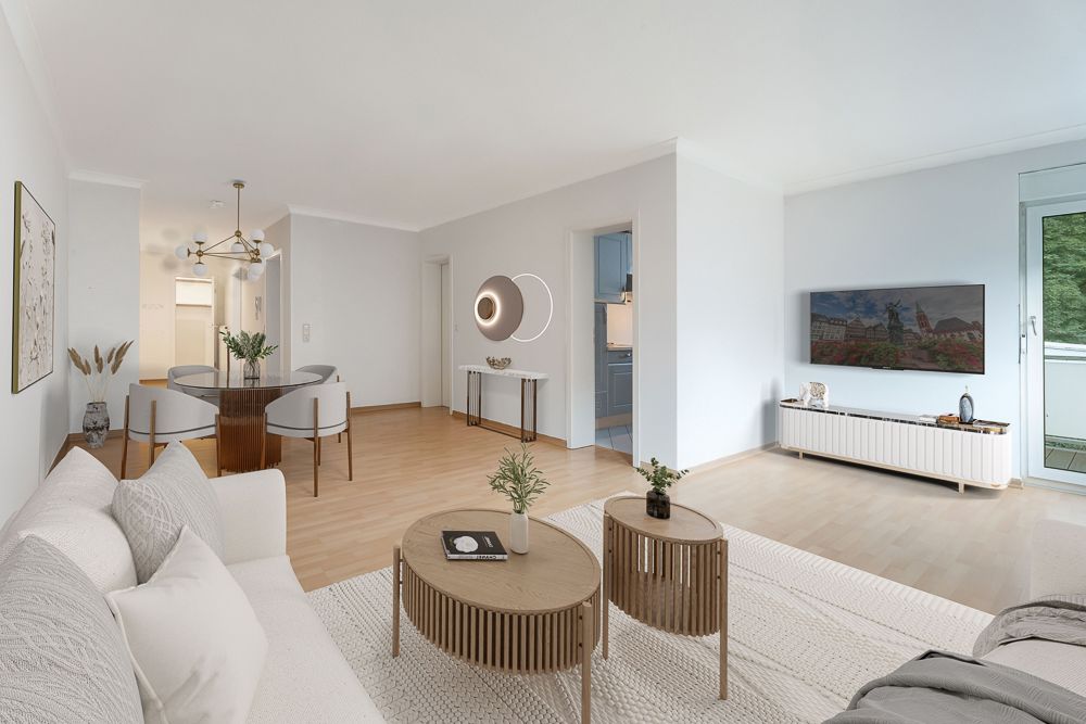 Helles Wohnzimmer mit Sofa, Couchtischen, Esstisch, TV und Zugang zum Balkon.