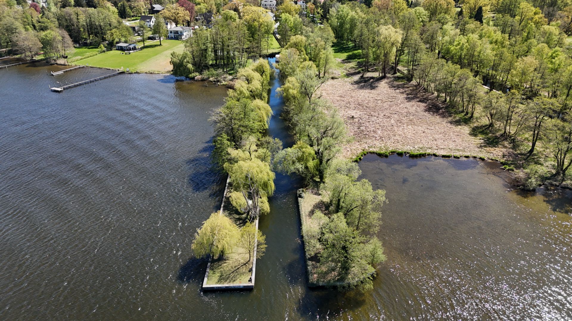 Luftaufnahme von einer von Bäumen gesäumten Wasserstraße zwischen zwei Uferbereichen.