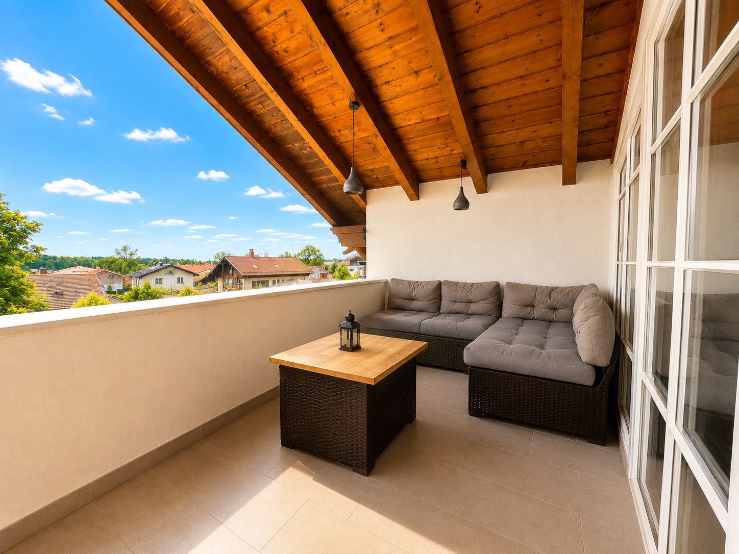 Überdachter Balkon mit Ecksofa, Couchtisch und Blick auf Nachbarhäuser.