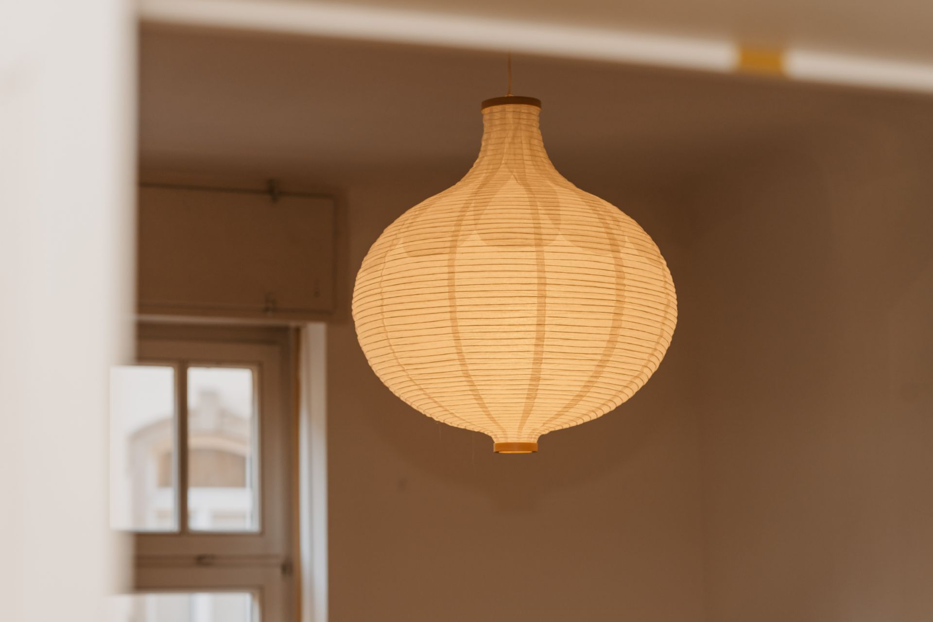 Runde Papierlampe hängt von der Decke in einem Zimmer mit Fenster.