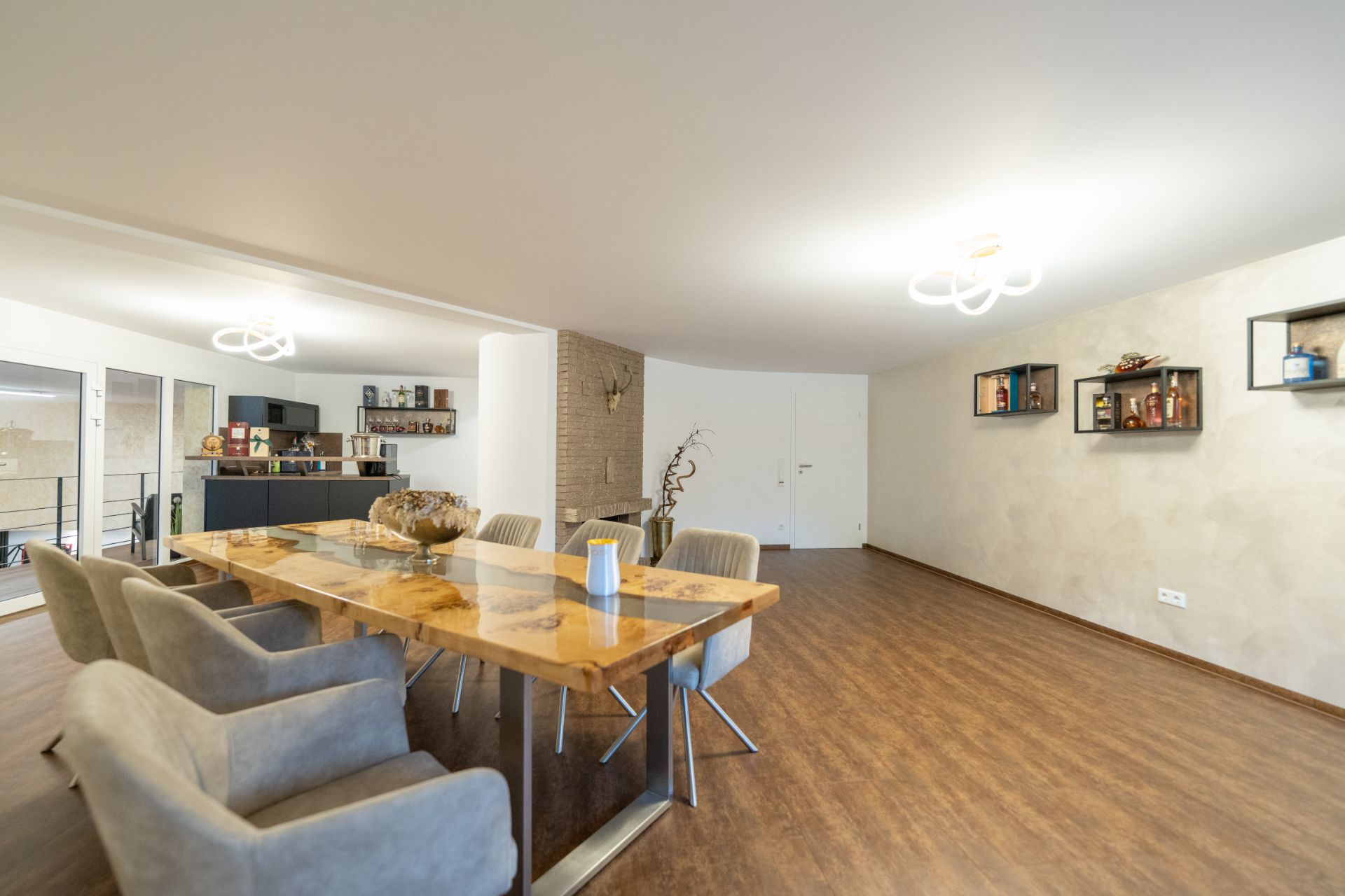 Geräumiges Esszimmer mit großem Holztisch, sechs Stühlen und Wandregalen auf Parkettboden.