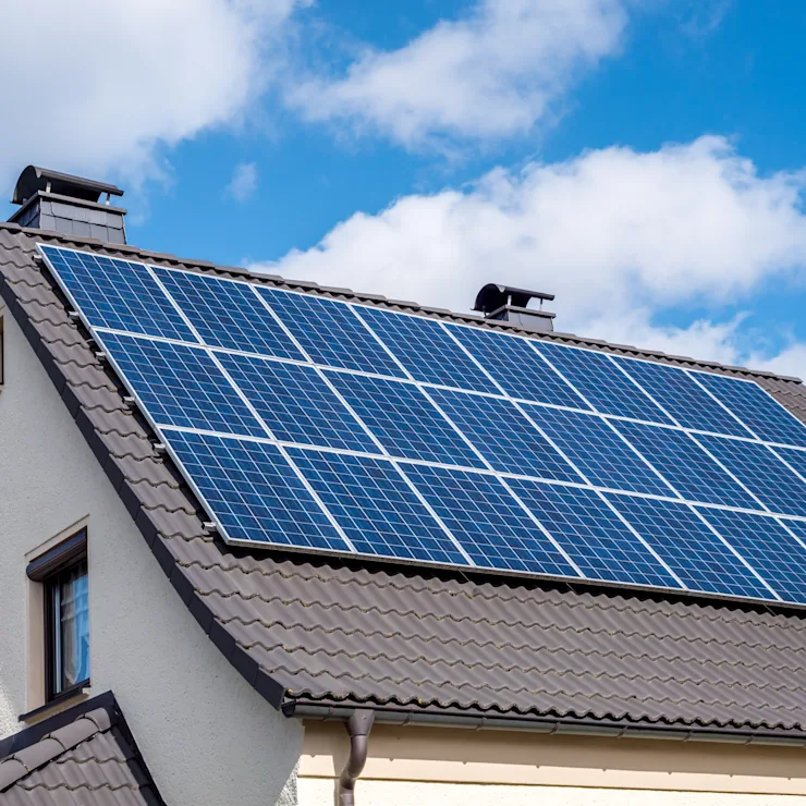 Dach eines Wohnhauses mit vielen Solarpanels unter blauem Himmel.