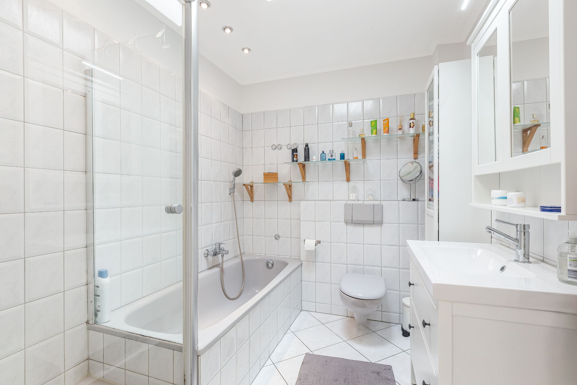 Modernes Badezimmer mit Badewanne, Dusche, Waschbecken, WC und weißen Fliesen.