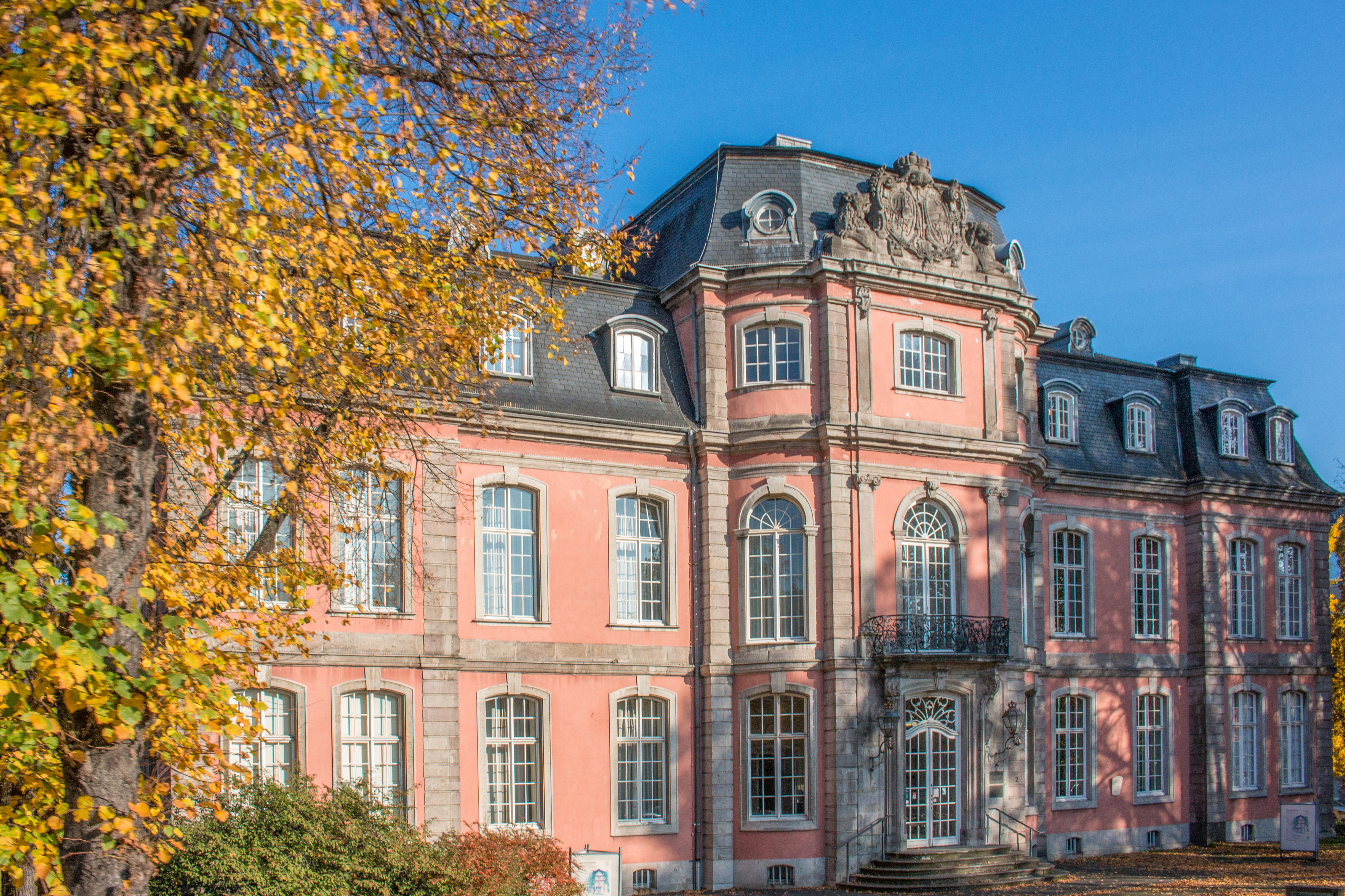 Historisches Wohngebäude mit aufwendigen Fassadendetails und kleinem Park im Vordergrund.