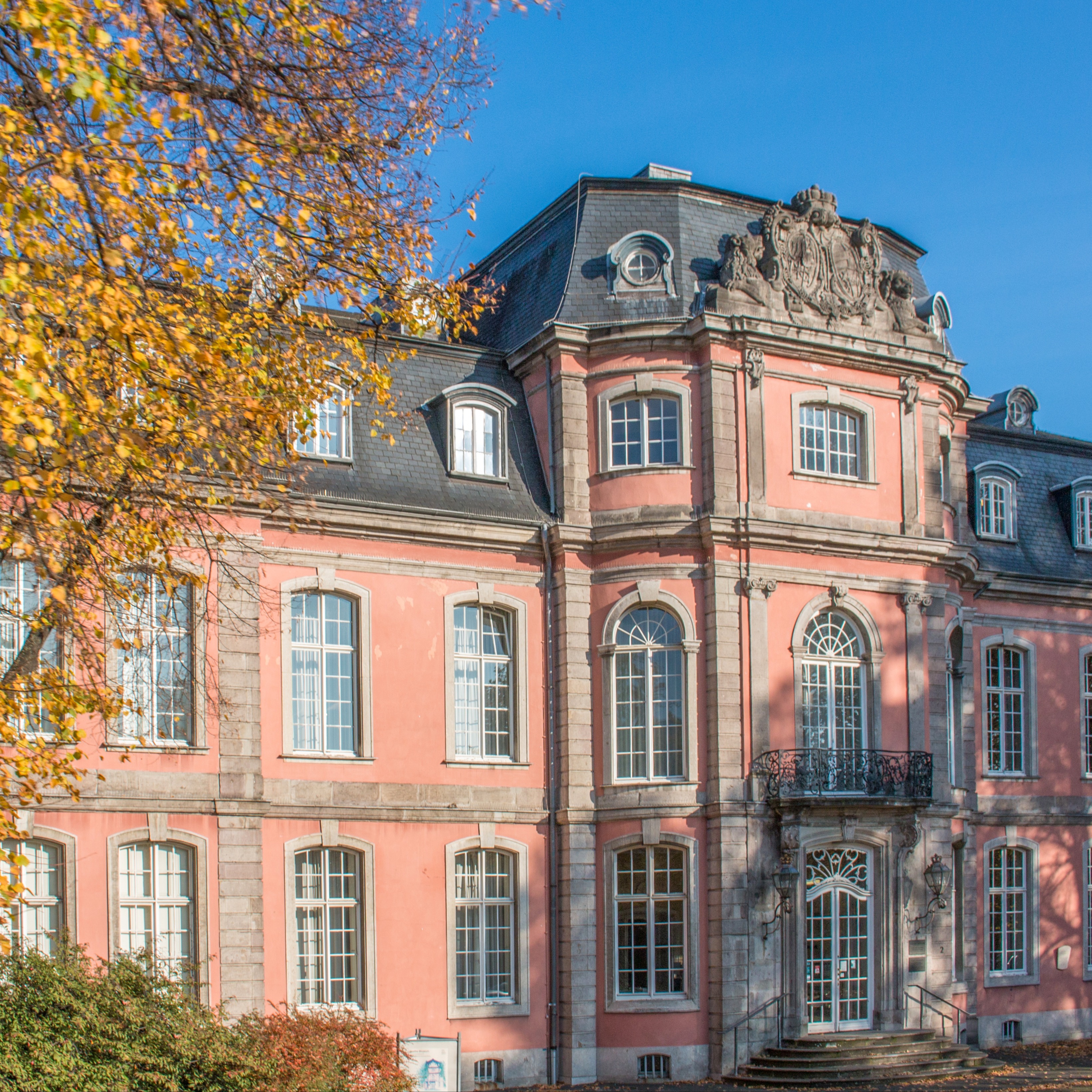Historisches Wohngebäude mit aufwendigen Fassadendetails und kleinem Park im Vordergrund.