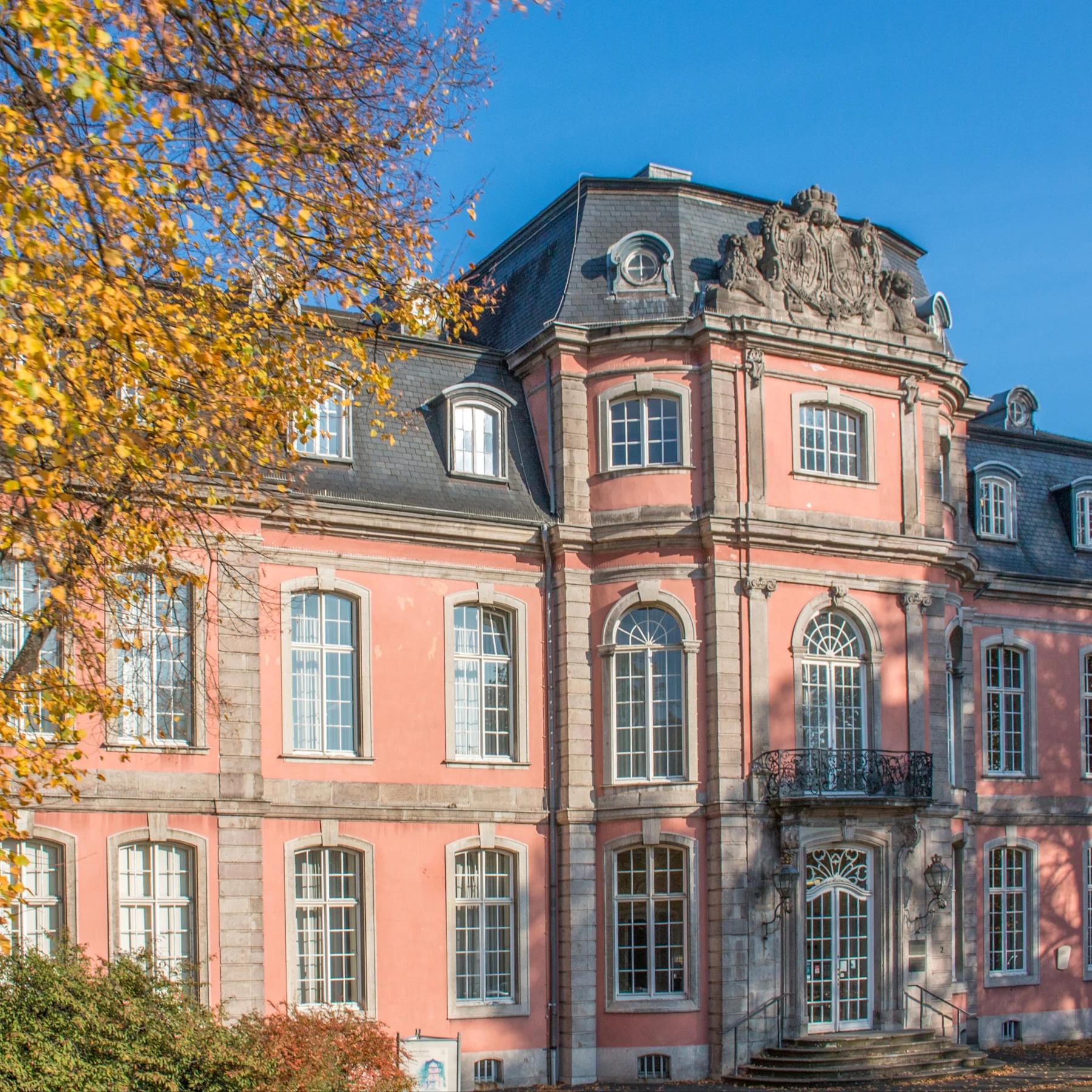 Historisches Wohngebäude mit aufwendigen Fassadendetails und kleinem Park im Vordergrund.