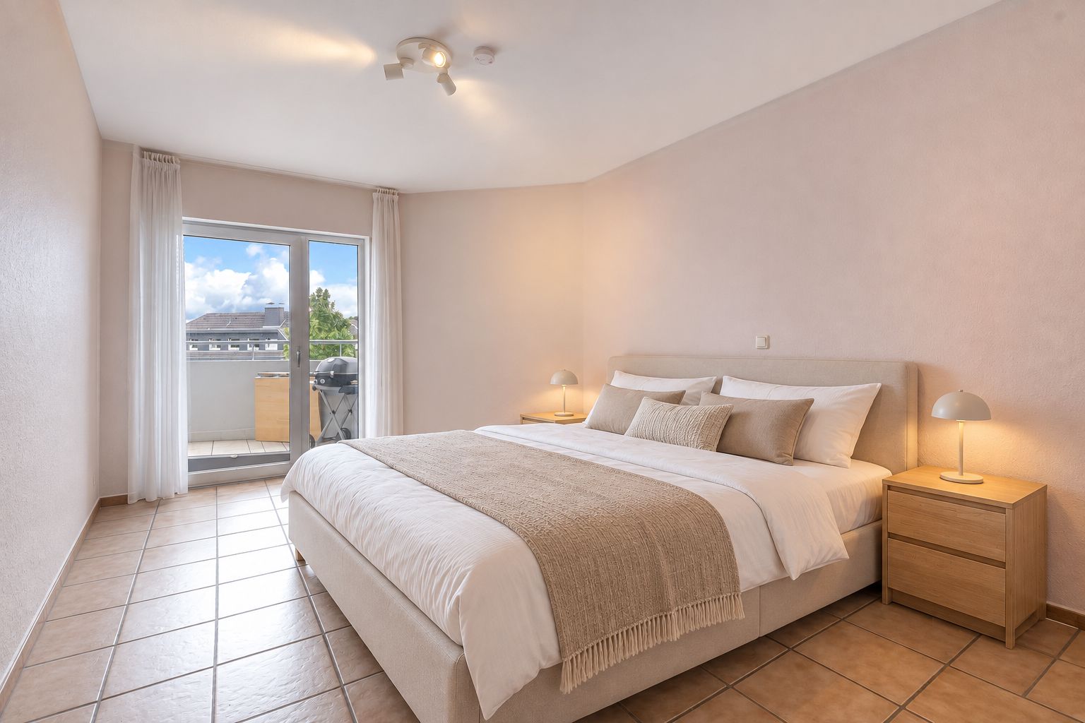 Helles Schlafzimmer mit Doppelbett, zwei Nachttischen und Zugang zu einem Balkon.