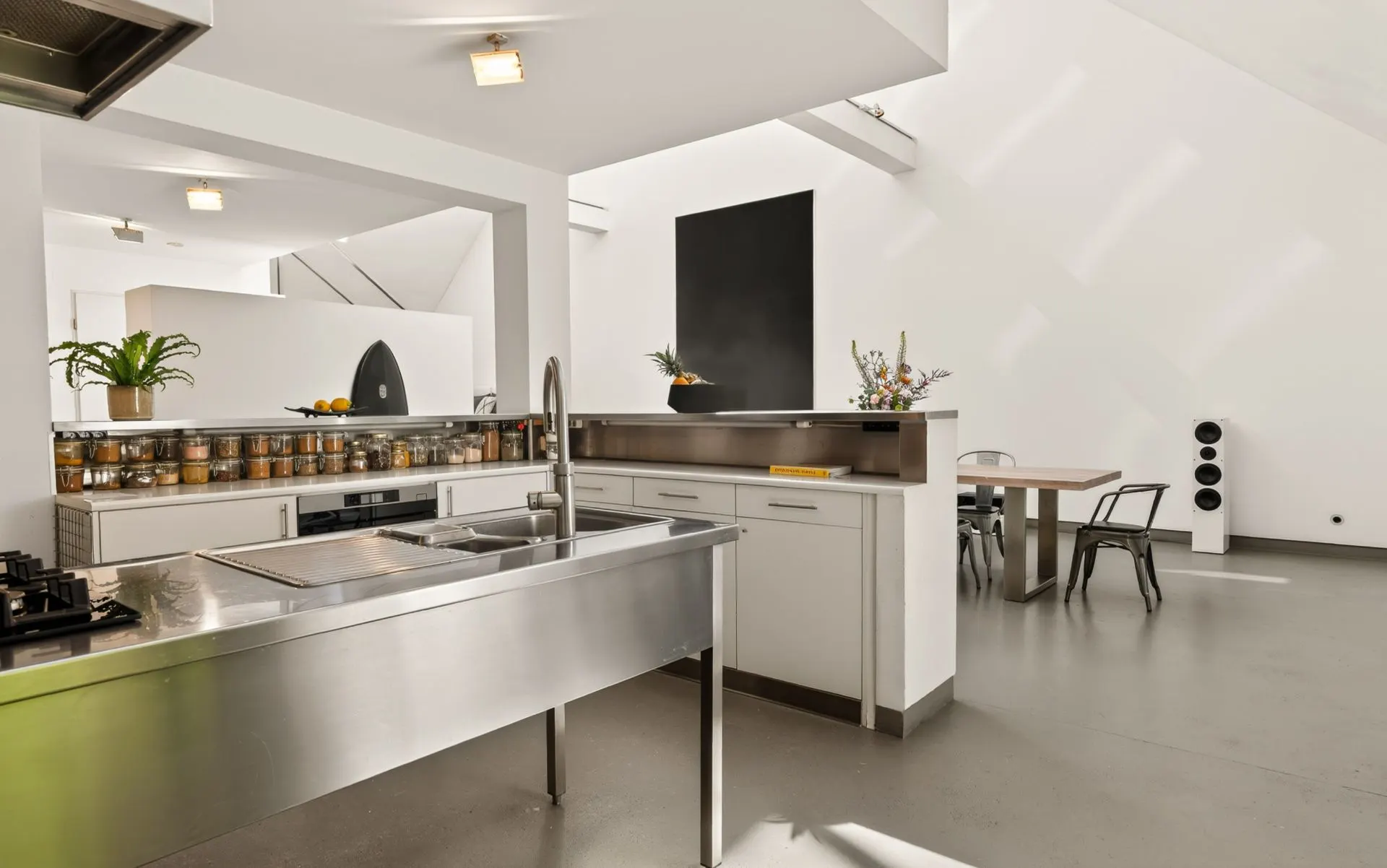 Moderne offene Küche mit Edelstahlspüle und Essbereich im Hintergrund.