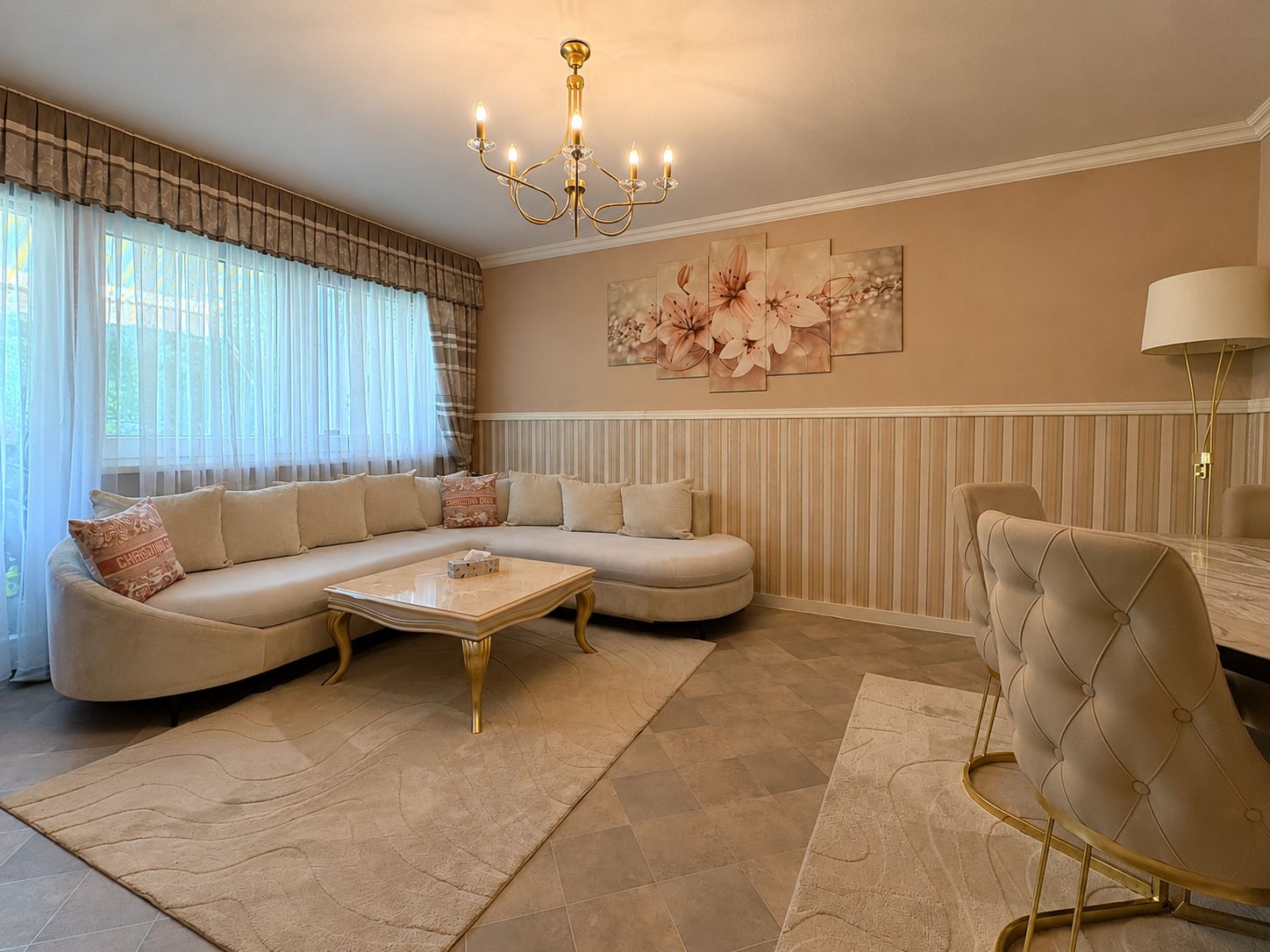 Helles Wohnzimmer mit beiger Eckcouch, Couchtisch, Teppich und Blumenbild an der Wand.