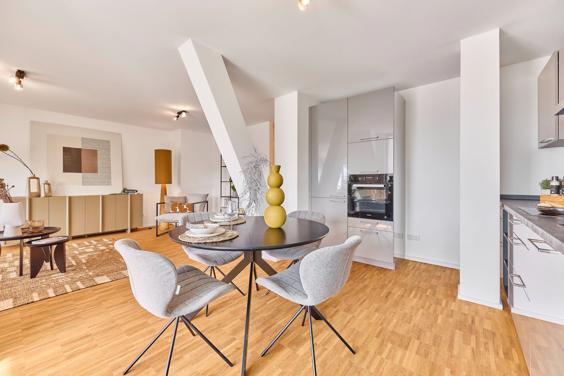 Helles Wohnzimmer mit Esstisch, Stühlen und moderner Küche auf Holzfußboden.