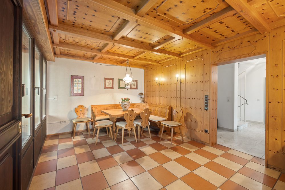 Holzverkleidetes Esszimmer mit Eckbank, Holztisch und Stühlen, gemusterter Fliesenboden.